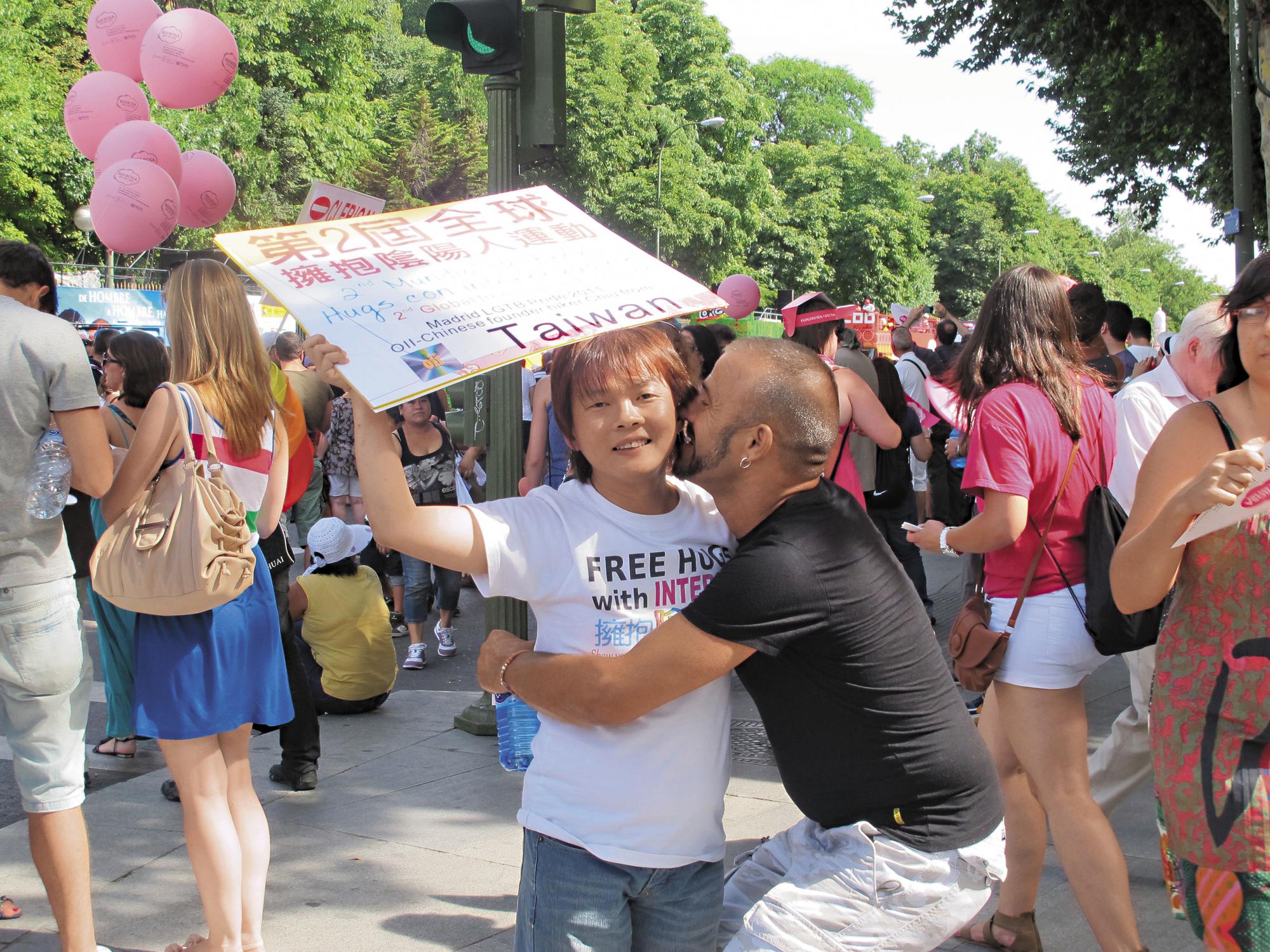 十多年來,丘愛芝參加國際陰陽人運動與同志運動,造訪數十個國家,見過上百位陰陽人,他總是隨身攜帶著「擁抱陰陽人」的標語牌子。(丘愛芝提供)