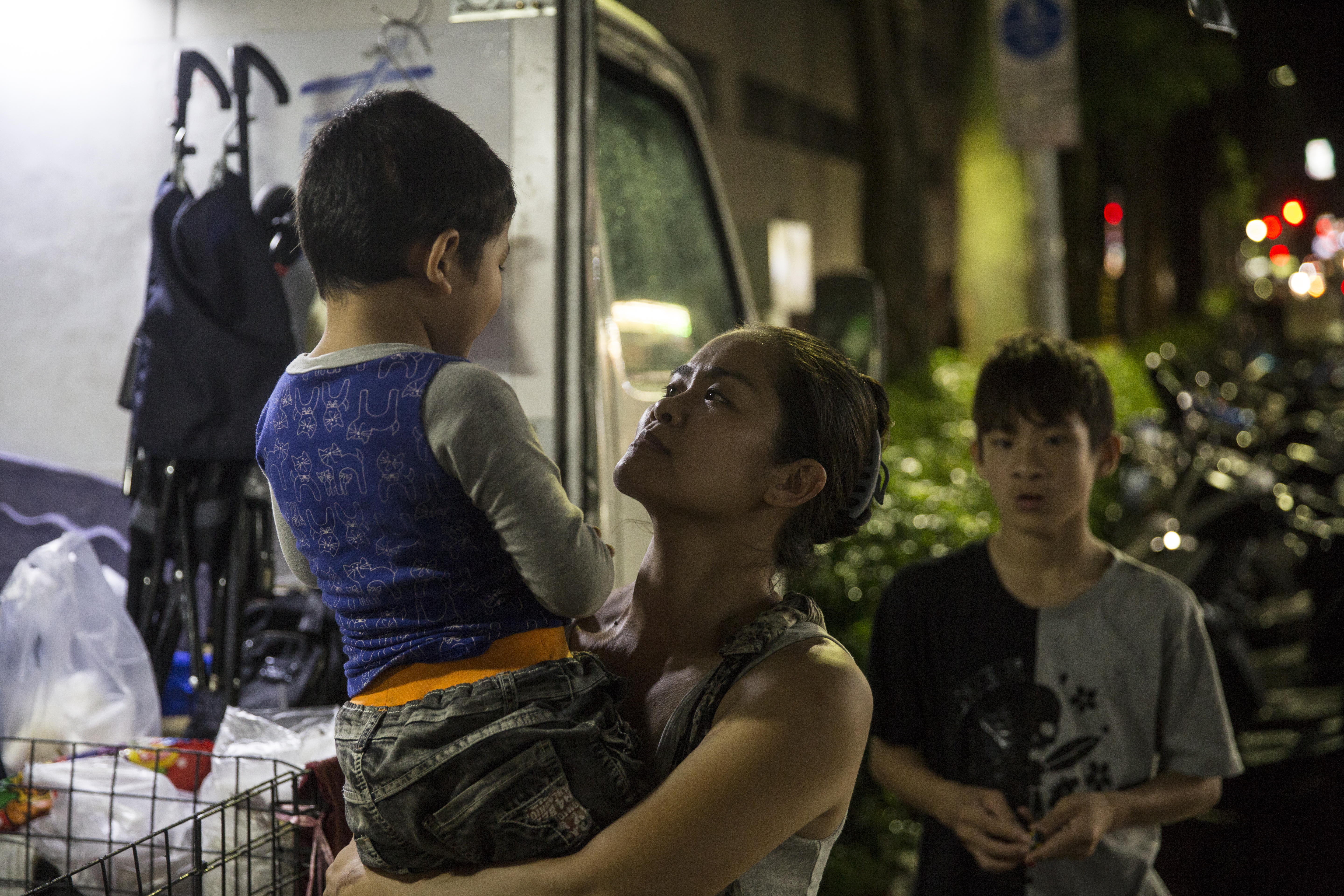 夜裡的西湖市場旁，李沂在工作的空檔陪伴孩子。