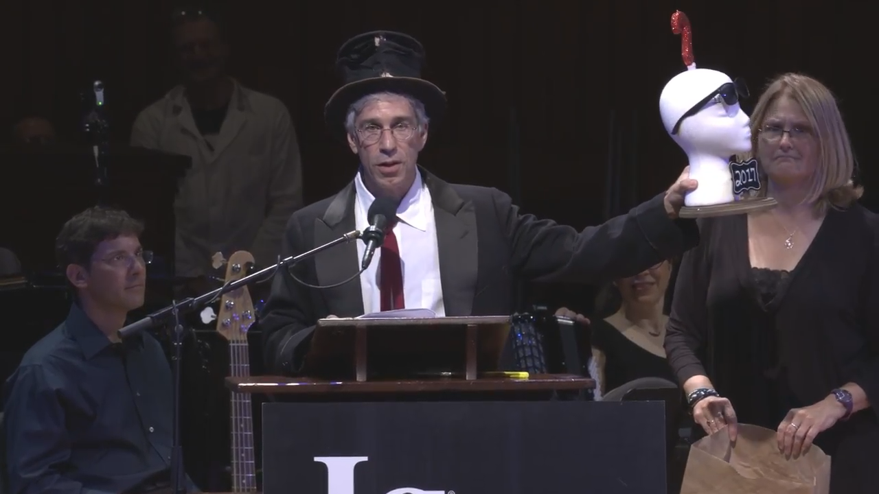 萬年司儀馬克亞伯拉罕斯也是搞笑諾貝爾獎的創辦人，他高舉今年的獎盃：是一座複製的問號在複製人頭上，因應今年主題：變化多端的不確定性。