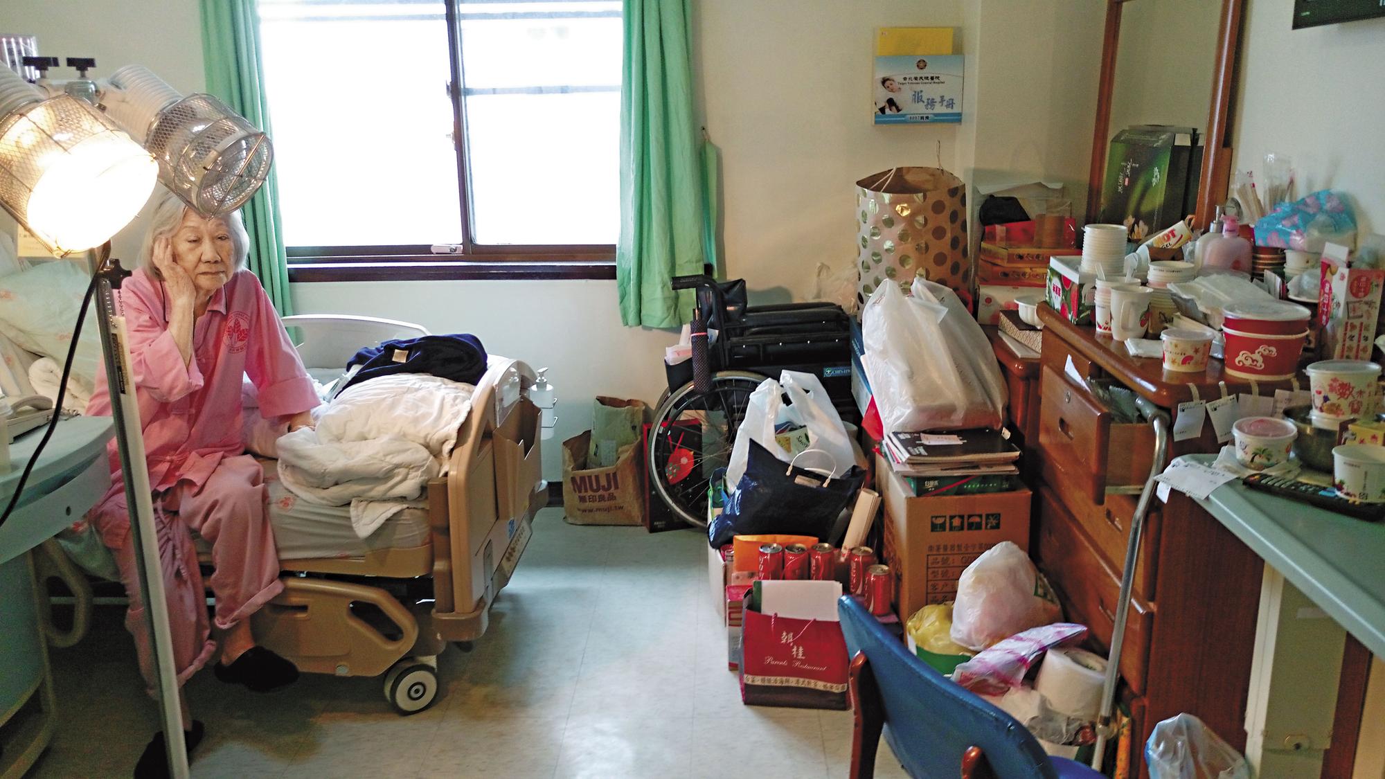 霸床老奶奶張周智逢住進榮總單人房已4年2個月，房內堆滿她的私人物品，床邊還擺放暖爐燈，老奶奶以院為家，已欠榮總逾774萬元的費用。