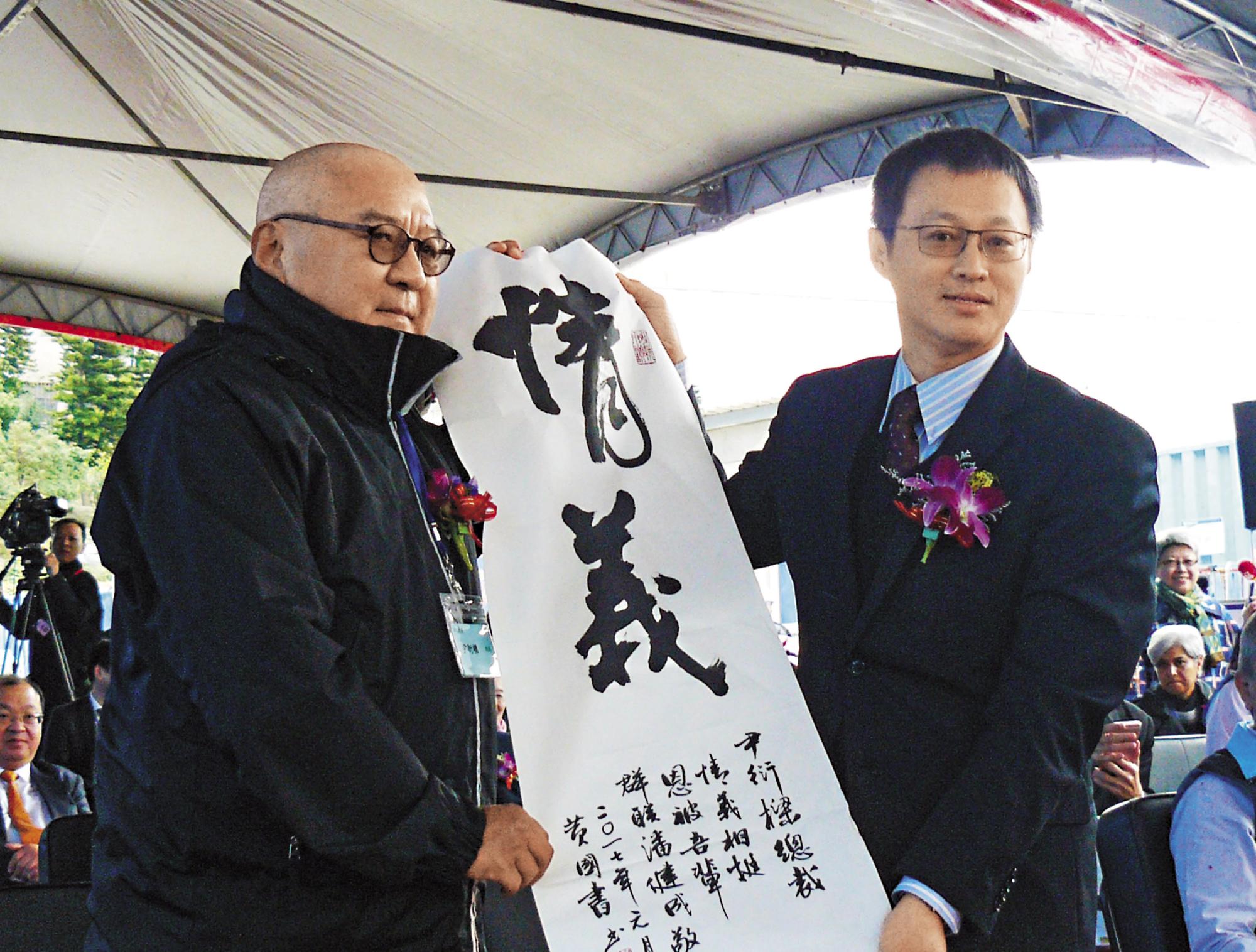 群聯因假帳風波導致股價重挫,潤泰集團董事長尹衍樑(左)砸下20億元買股相挺,潘健成(右)特別贈送墨寶「情義」致謝。(中央社)
