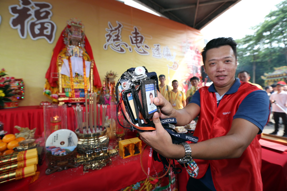 鴻海人拿員工證過爐求平安。