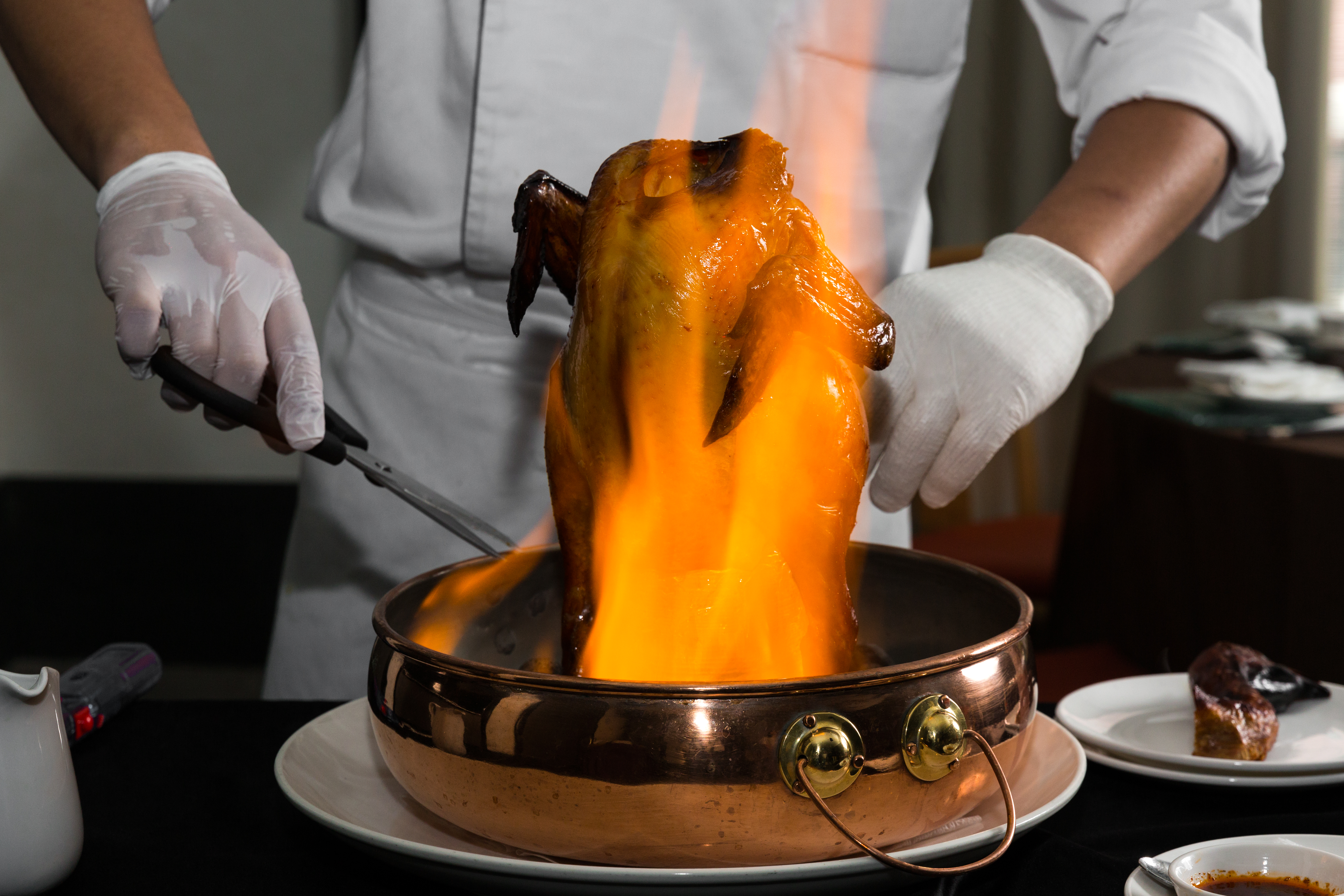 鍋底滾燙的麥飯石遇上高粱藥酒，點火後火舌一路沿著雞身向上，視覺效果強，鼻尖也嗅聞到濃烈酒香。