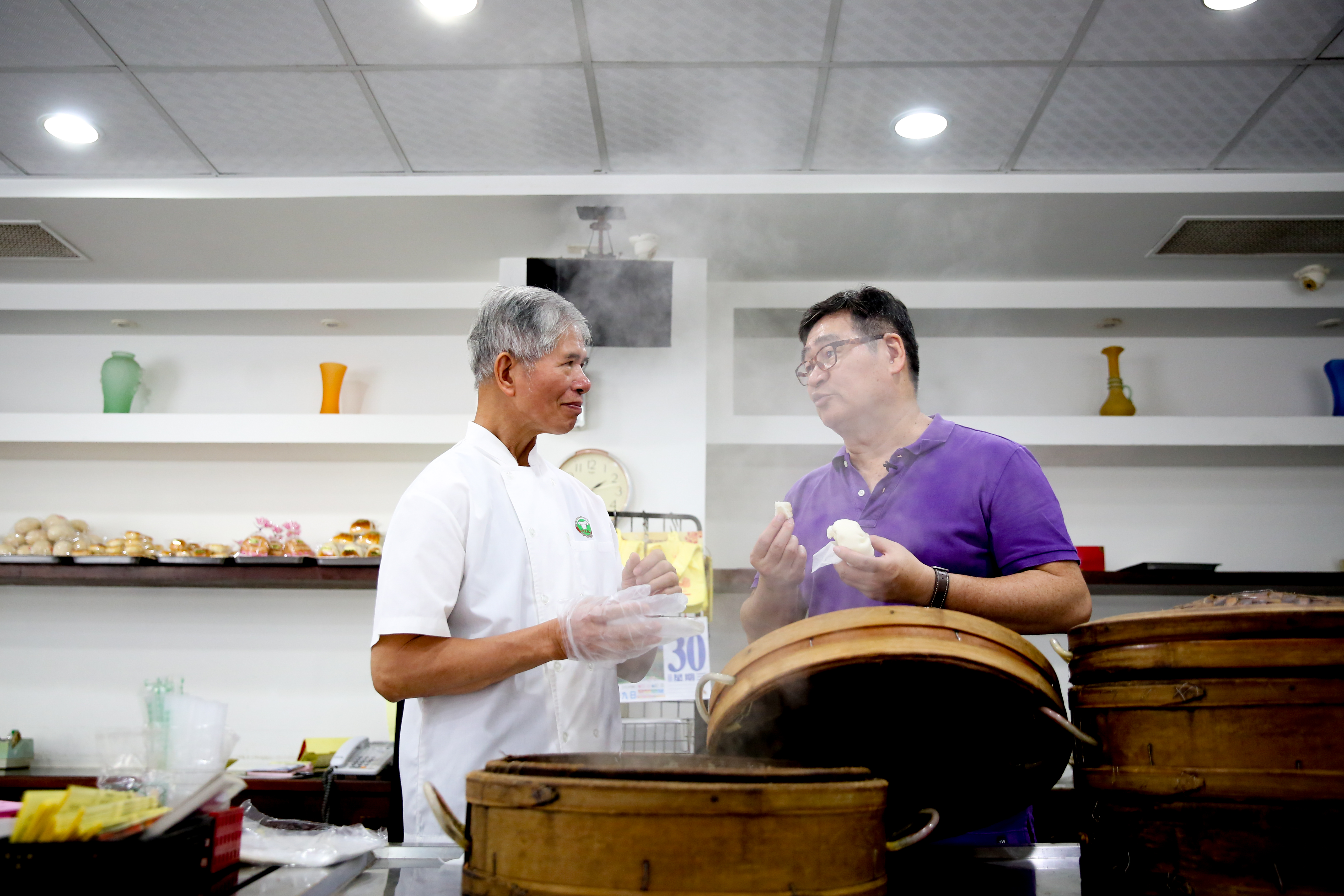 文藝大叔王浩一（右）帶我們走訪台南私房老餅店，他和「萬川號」老師傅蔡煌明（左）談起店裡百年老包子的身世。