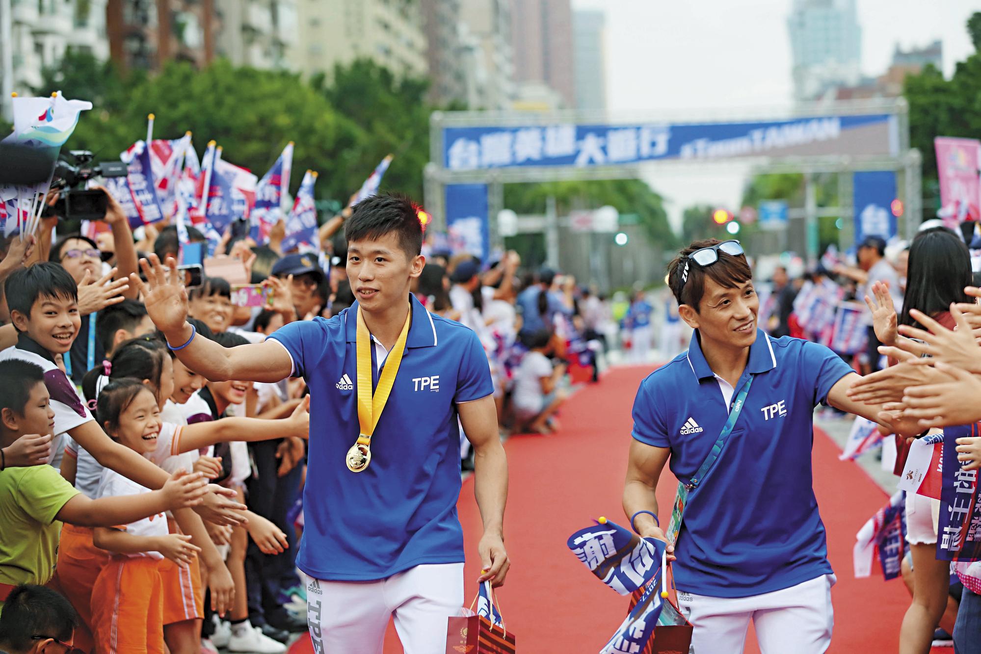 在「世大運台灣英雄大遊行」上，李智凱（左）和林育信（右）一同接受民眾喝彩。
