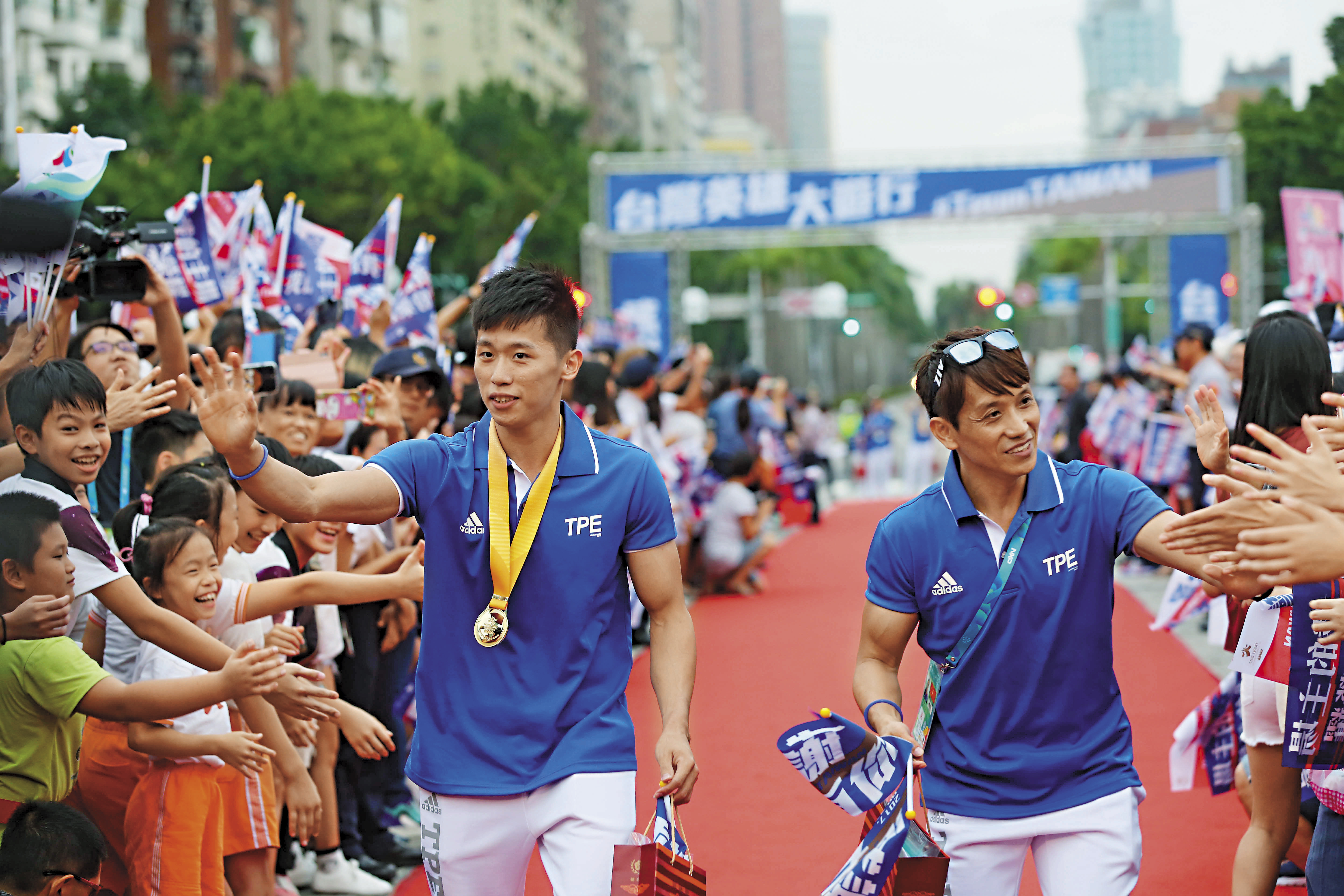 在「世大運台灣英雄大遊行」上，李智凱（左）和教練林育信（右）一同接受民眾喝彩。