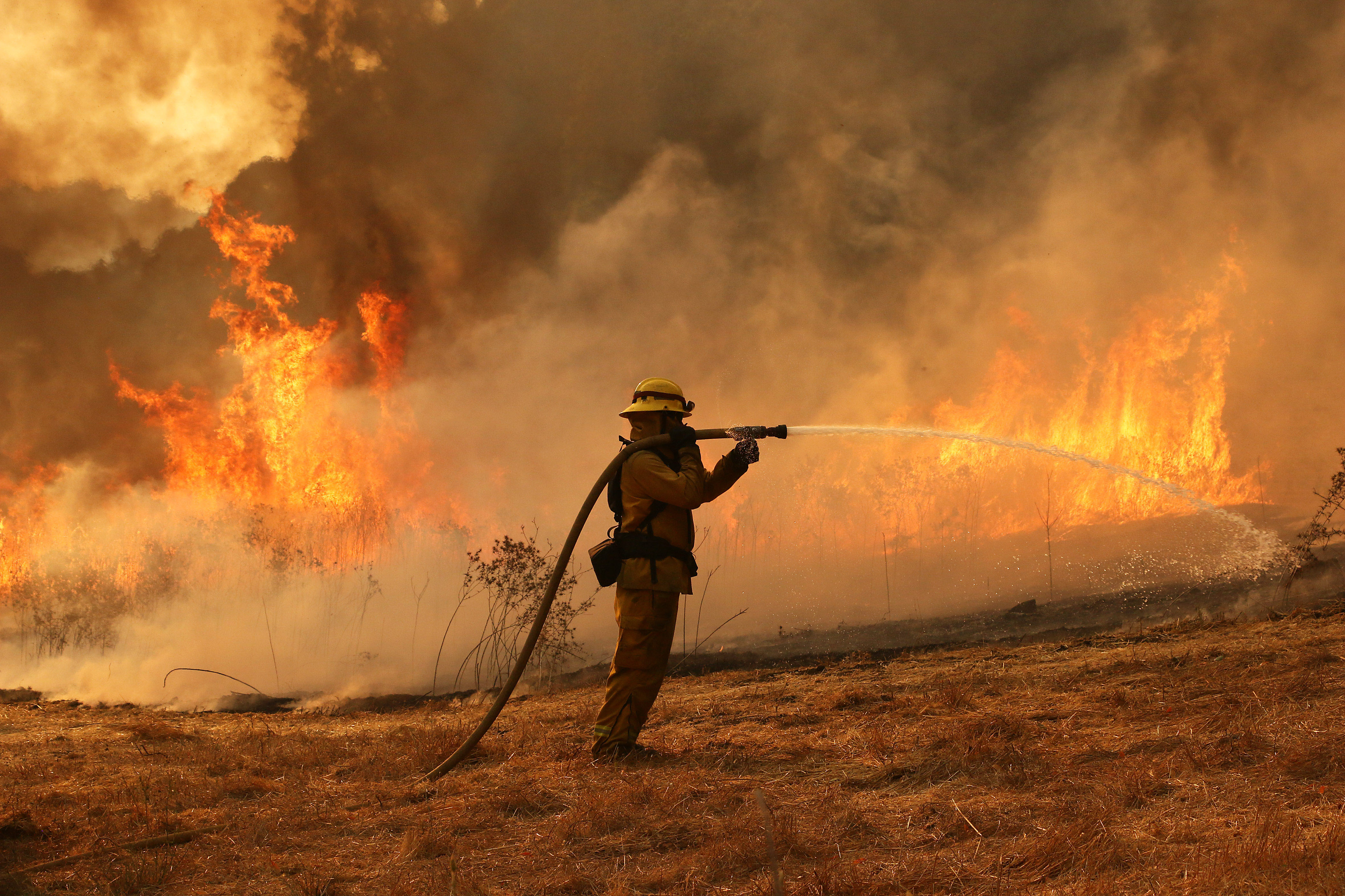 2017年10月11日，美國加州聖塔羅莎一名消防人員在大火中正努力搶救東班尼特谷路的民宅。（東方IC）