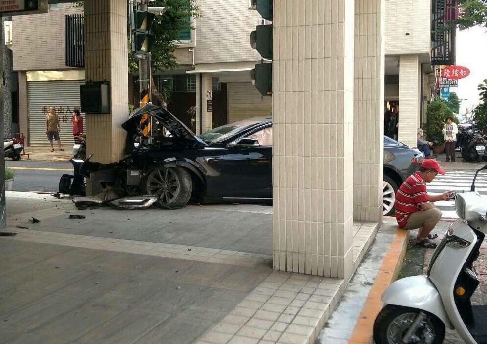 價值300萬的「特斯拉」電動車車禍,疑似車主者在一旁猛打手機,顯得相當苦惱。(翻攝網路)