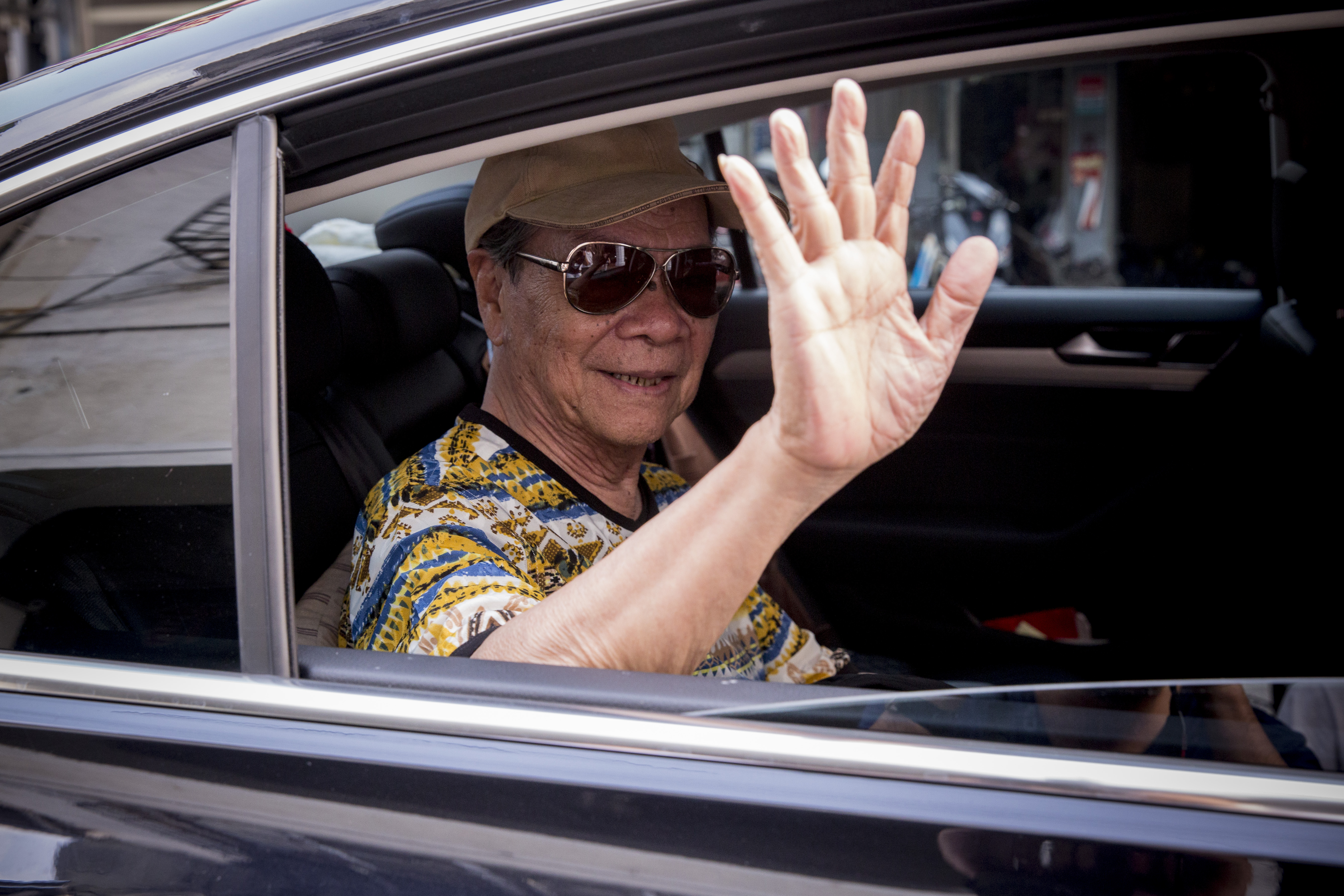戴著墨鏡，坐上黑車，搖下車窗揮手的黃俊雄，像是一位退休的老教父。