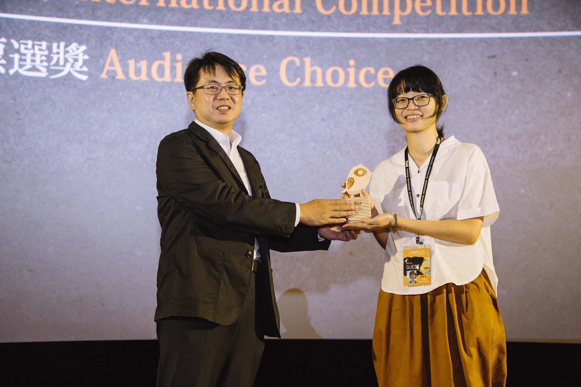 台中市影視發展基金會執行長林盈志（左）頒發觀眾票選獎給《關於他的故事》導演楊詠亘。（台中國際動畫影展提供）