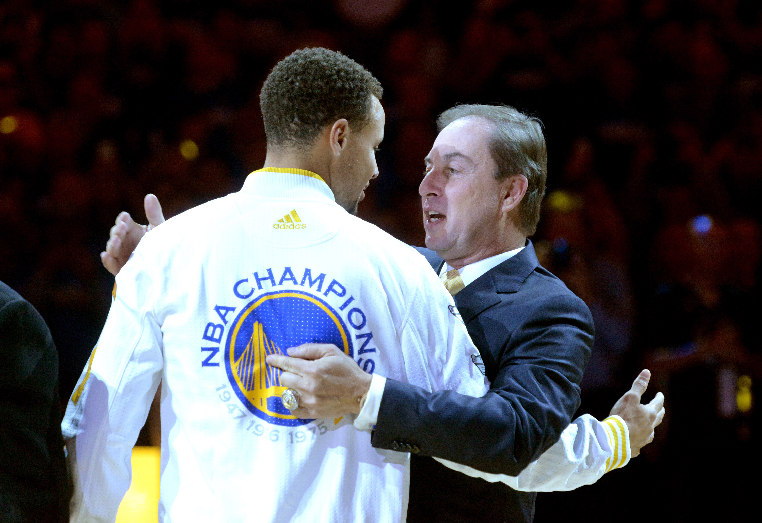 美國職籃NBA金州勇士球星柯瑞（左）與球團老闆拉各布（右）在一場比賽前相擁致意。（東方IC）