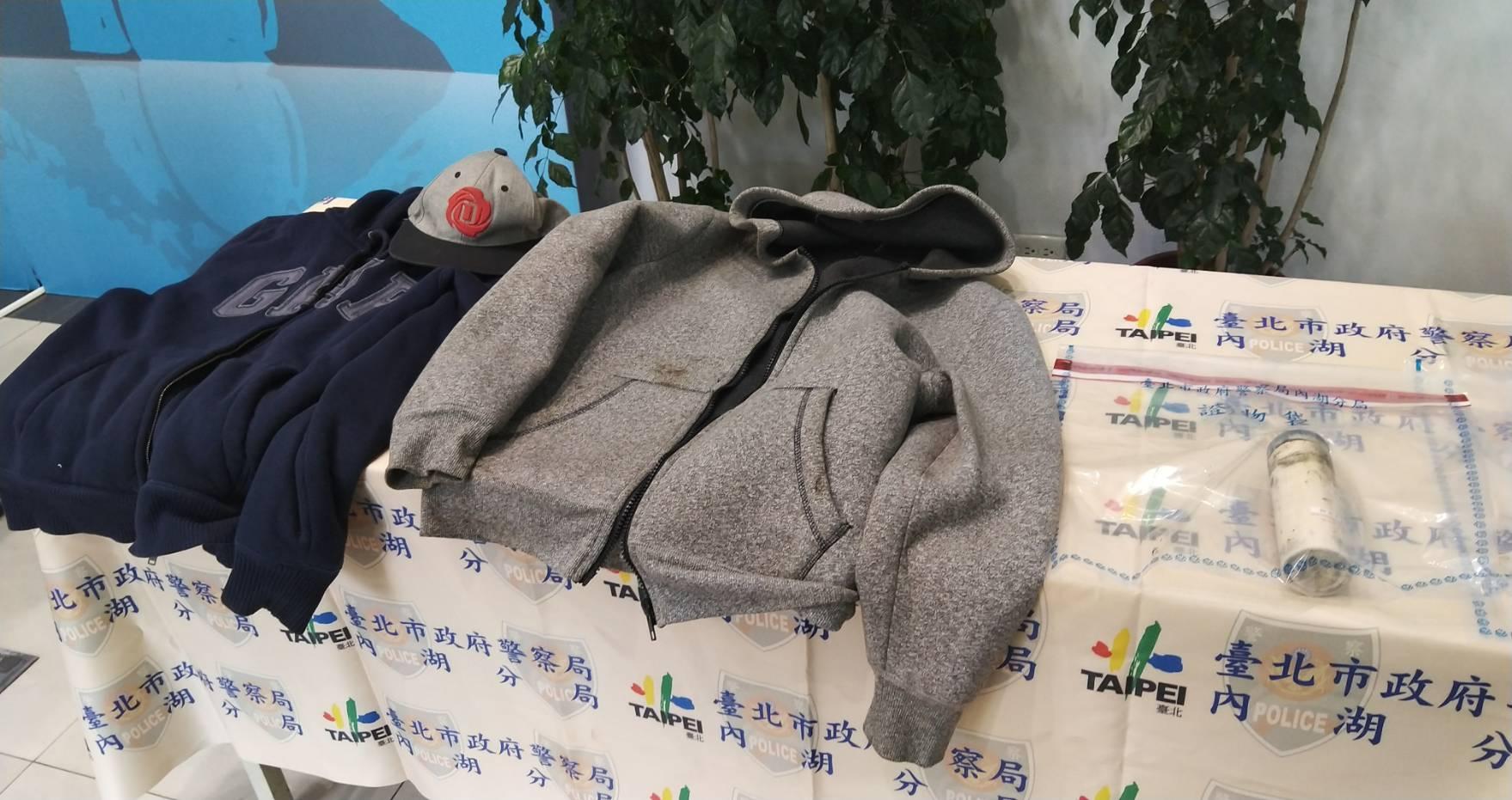 兩名大學生埋伏作案時的外套,一旁是用來裝瀝青潑灑的大瓶口咖啡罐。(翻攝畫面)