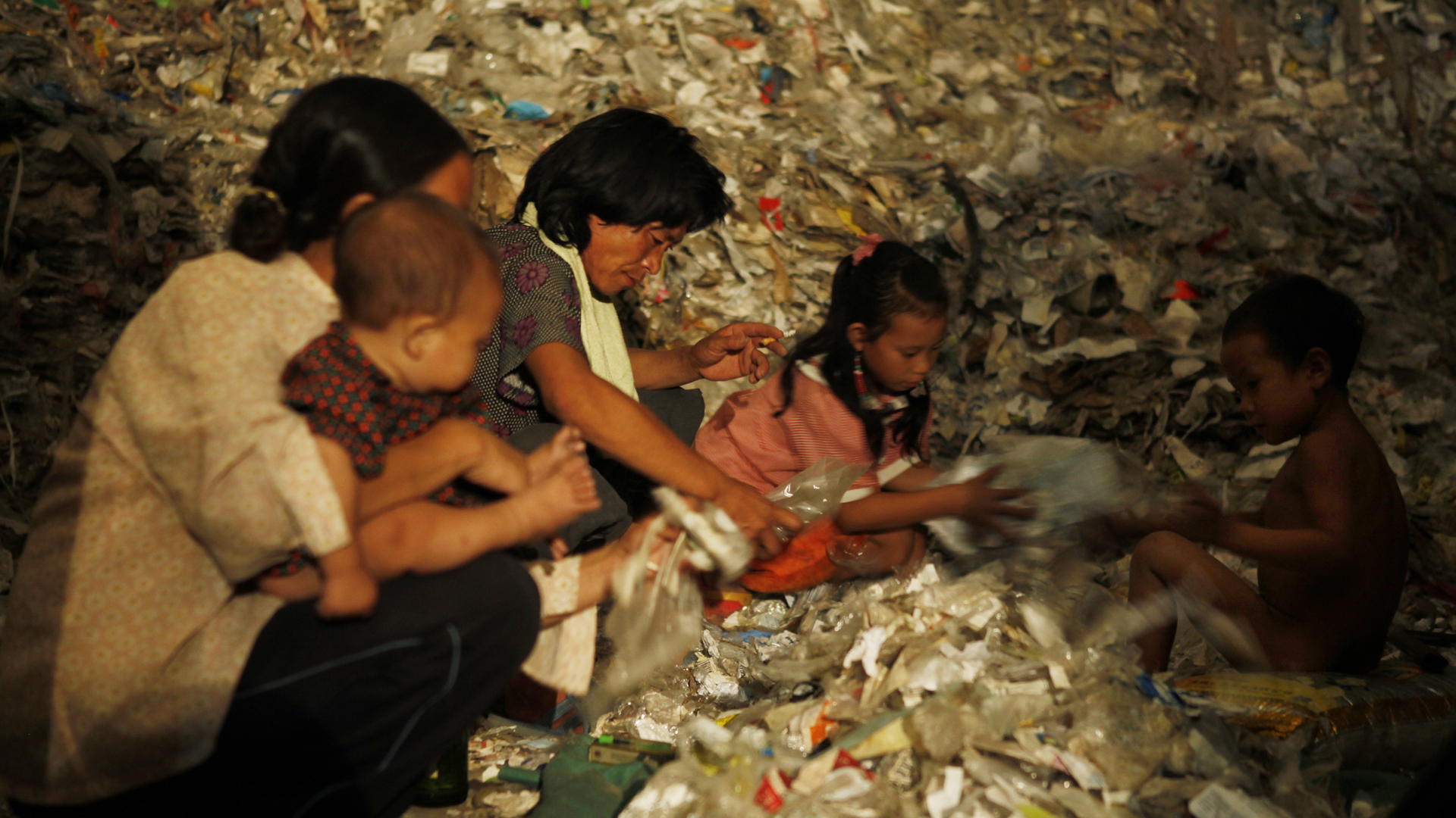 來自四川大涼山的彝族家庭在山東塑料工廠打工，生活在塑料堆之中。 （CNEX提供）