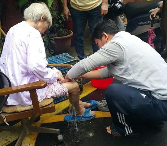 失智黃姓婦人在住家樓下跌倒,里長林華偉親手為她洗穢物。(翻攝畫面)