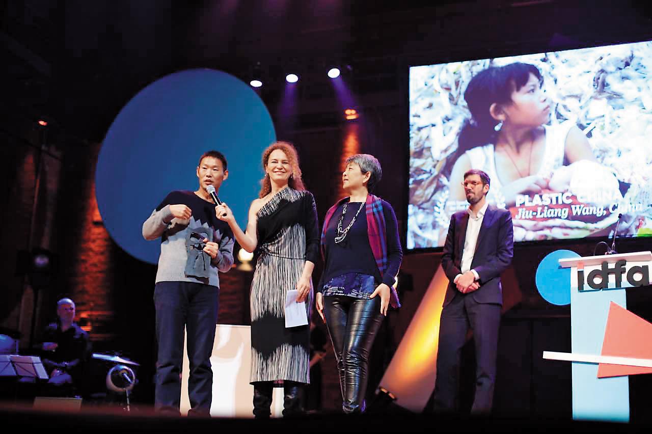 《塑料王國》獲阿姆斯特丹紀錄片影展新導演單元評審團特別獎,王久良(左一)登台領獎。右二為製片陳玲珍。 (王久良提供)