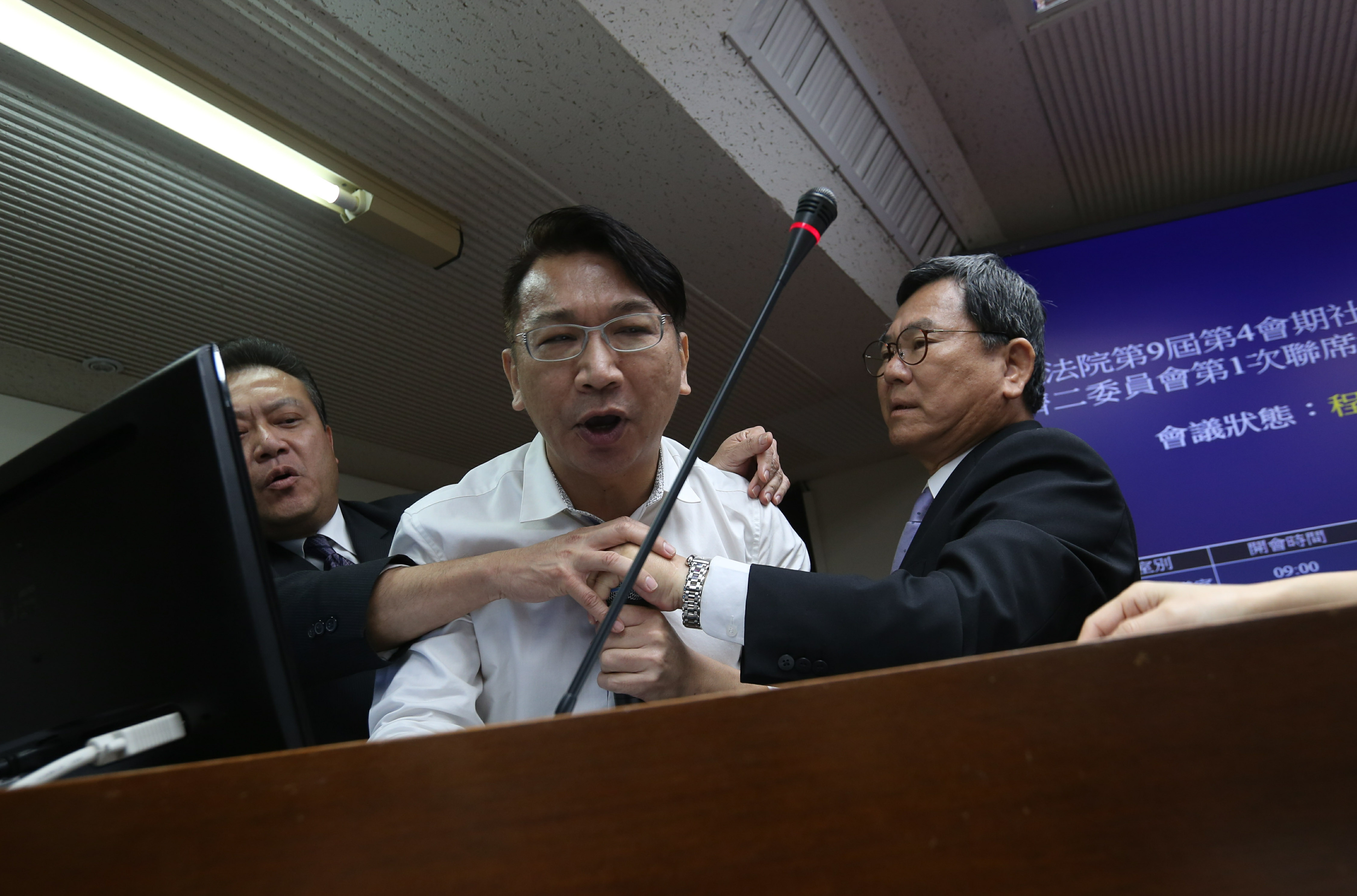 時代力量立委徐永明霸佔發言台，民進黨立委陳明文（右）、蘇震清（左）欲搶走徐手上的無線麥克風。