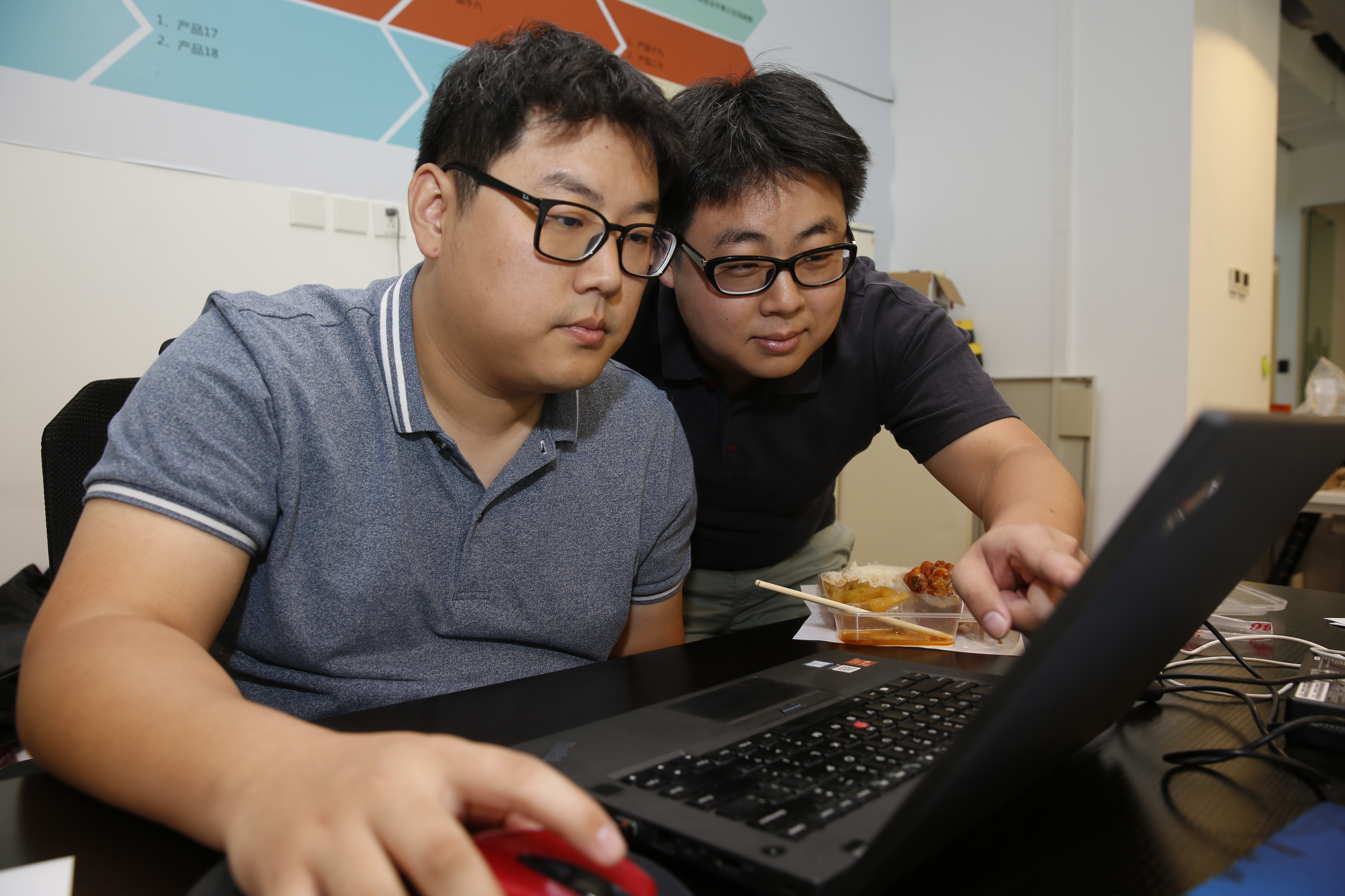 在大陸創業競爭激烈、分秒必爭，酆尚寬（左）連吃午餐都和弟弟酆偉寬（右）討論公事，在電腦前解決。