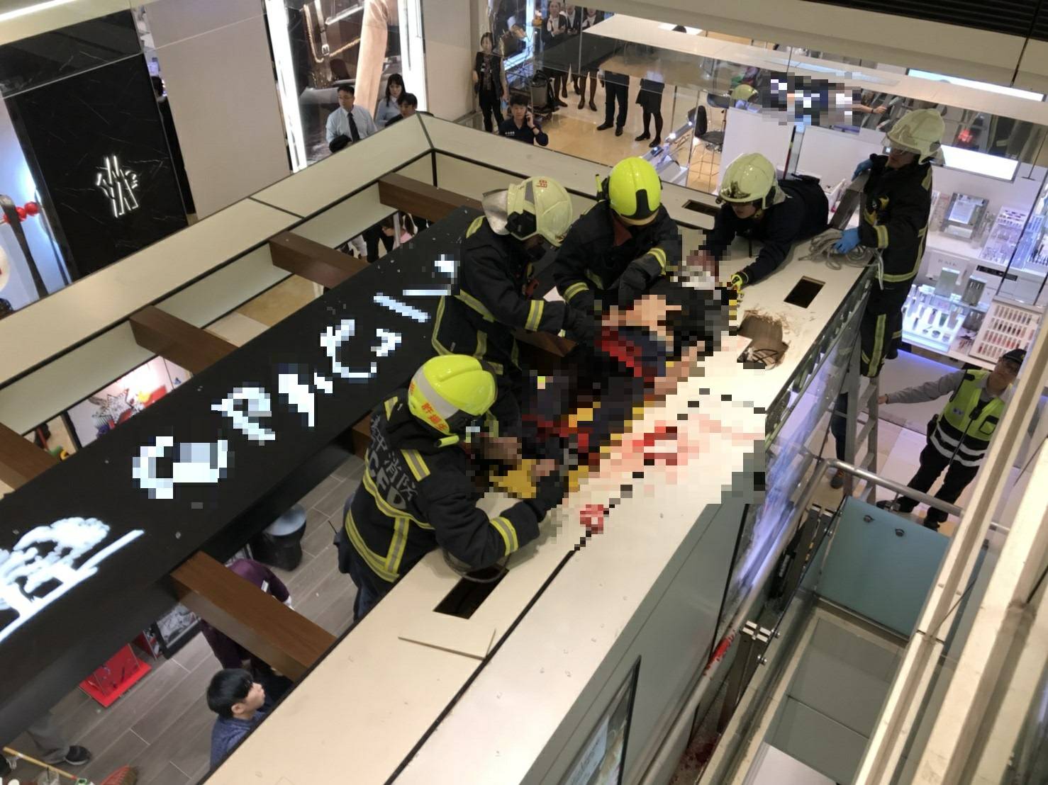 消防人員以雙節梯將墜落一樓化妝品專櫃的黃男送醫急救。（消防局提供）