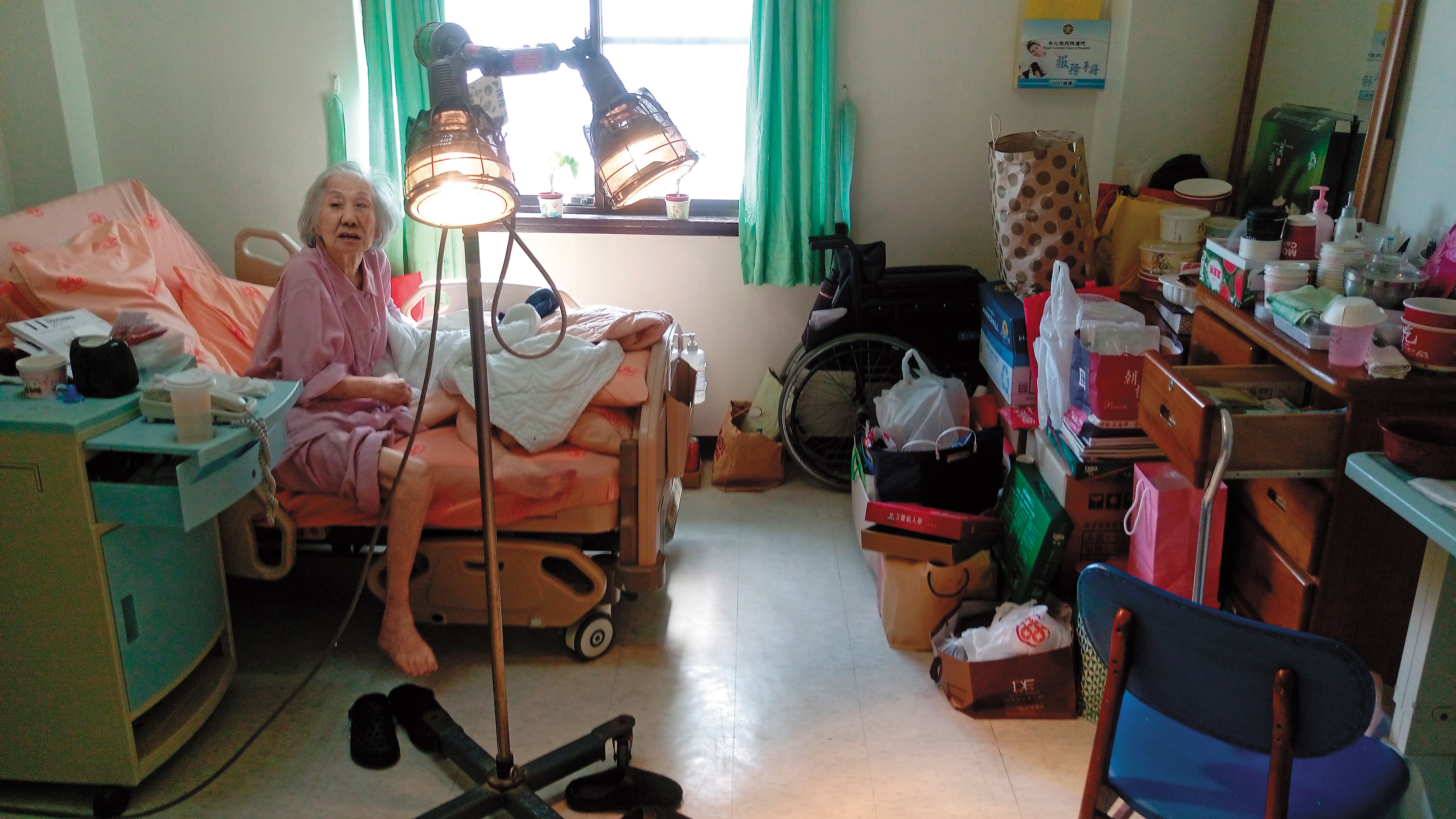 榮總已切掉病房冷氣，但老奶奶怕冷不怕熱，將2盞電暖燈全開，熱到要捲起褲管及衣袖。