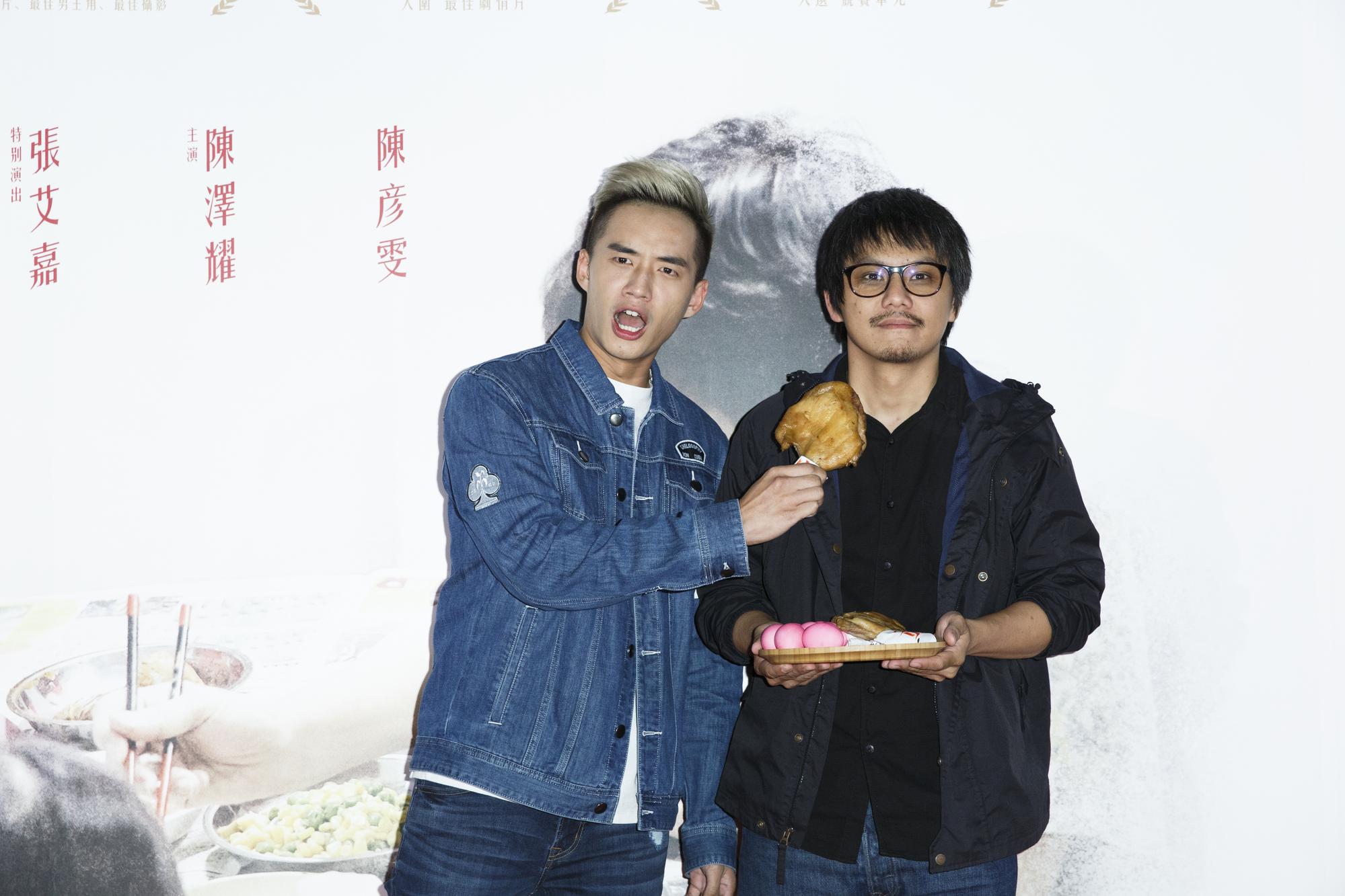 電影公司安排陳澤耀(左)拿著片尾出現的雞腿,與導演陳勝吉象徵票房大賣。