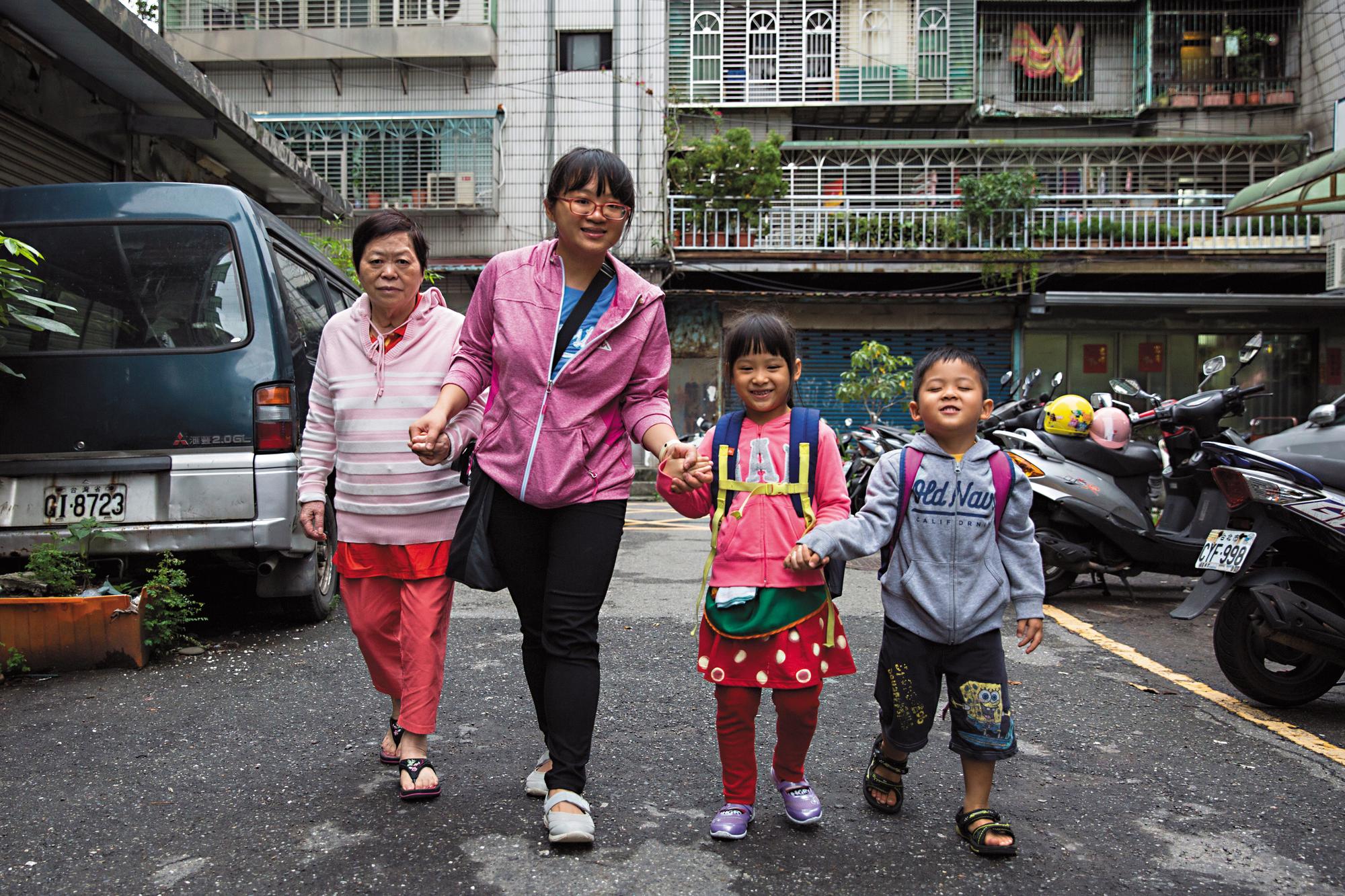 許琇惠(左2)牽著母親(左1)、女兒(右2)、兒子(右1)在家門前的巷子拍照。面對失智症只退不進的情況,許琇惠樂觀看待,她說:「活一天就是賺一天。」