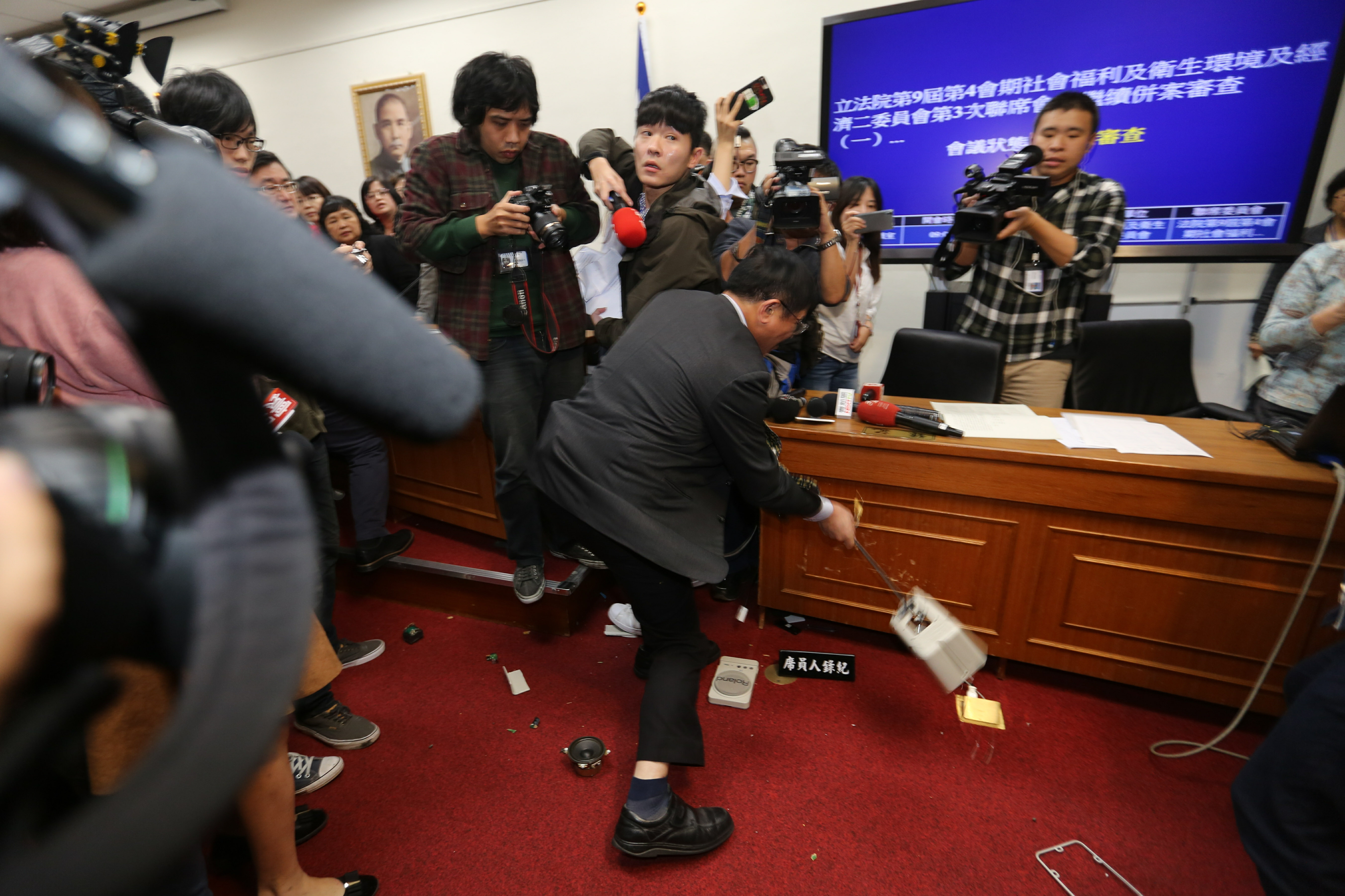 不滿民進黨強行表決，國民黨立委鄭天財憤而將會場擴音器砸毀。