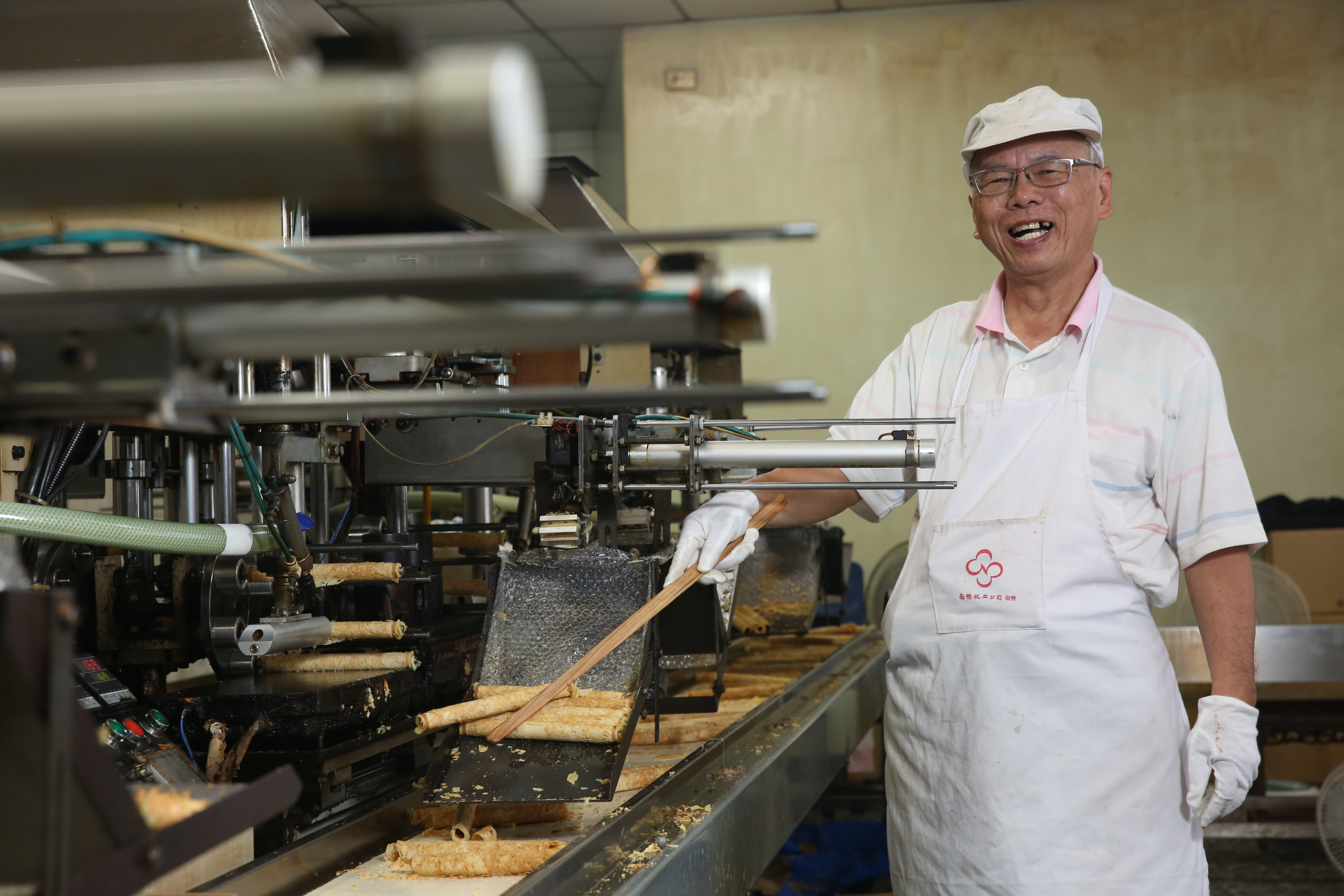 曾華誠每天7點上工,拿著如同教鞭的木頭長棍,熟練地將煎好的蛋捲依序撥下,活像蛋捲廠裡的訓導主任。