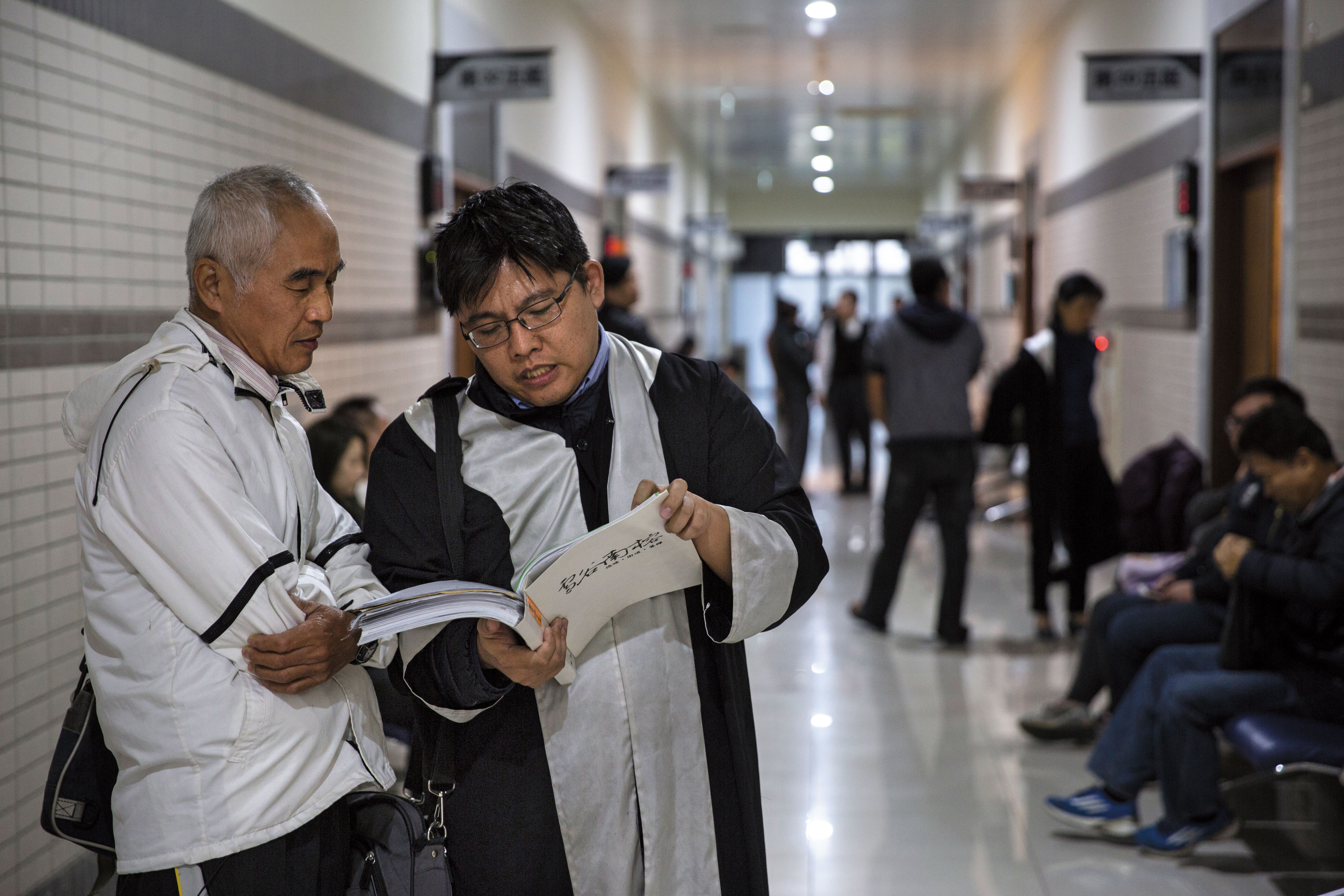 這天，邱顯智來到新竹地方法院，等待開庭的前夕，正忙著跟當事人討論案情。