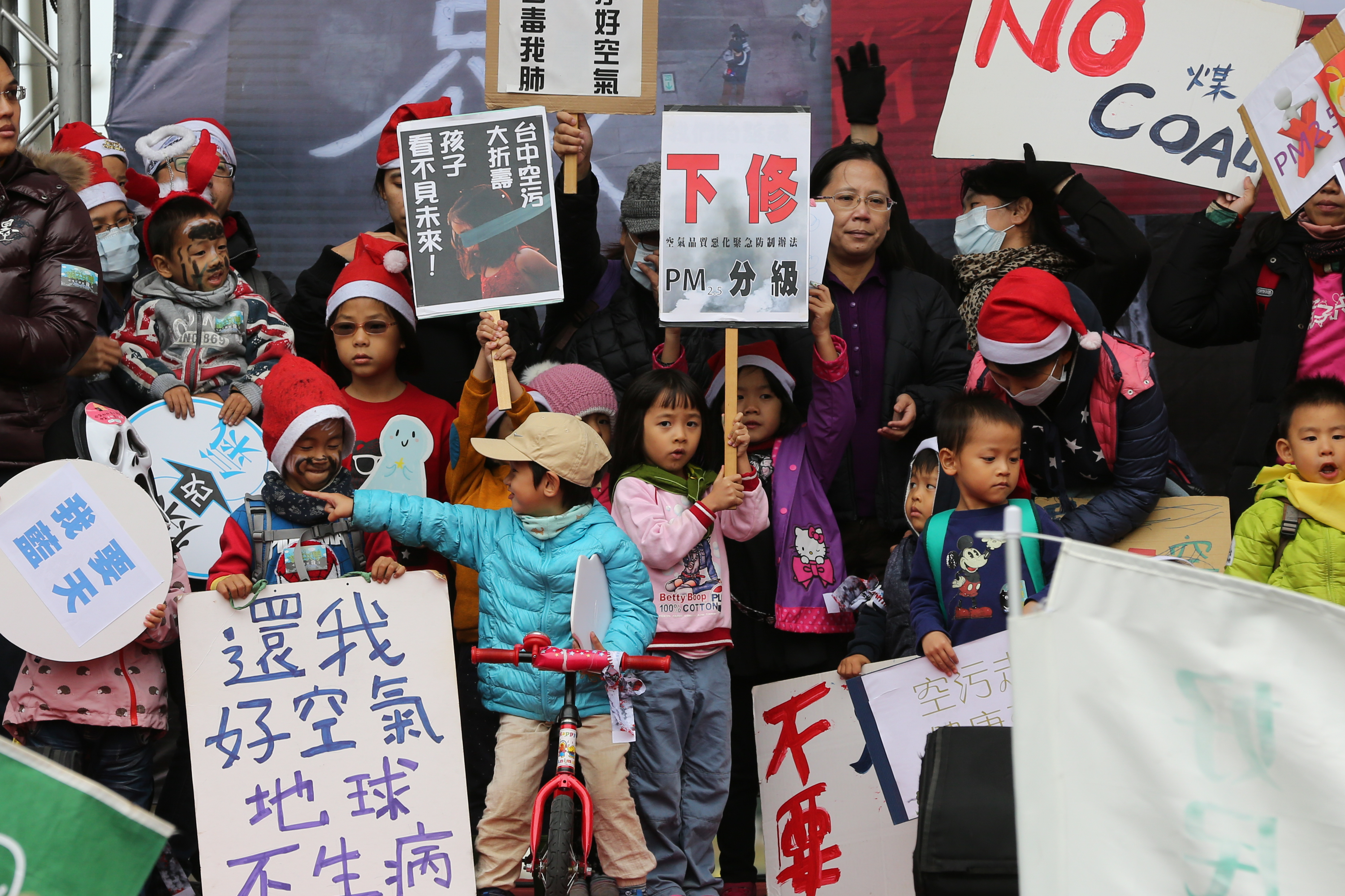 小孩在遊行結束後上台舉著抗議看板。