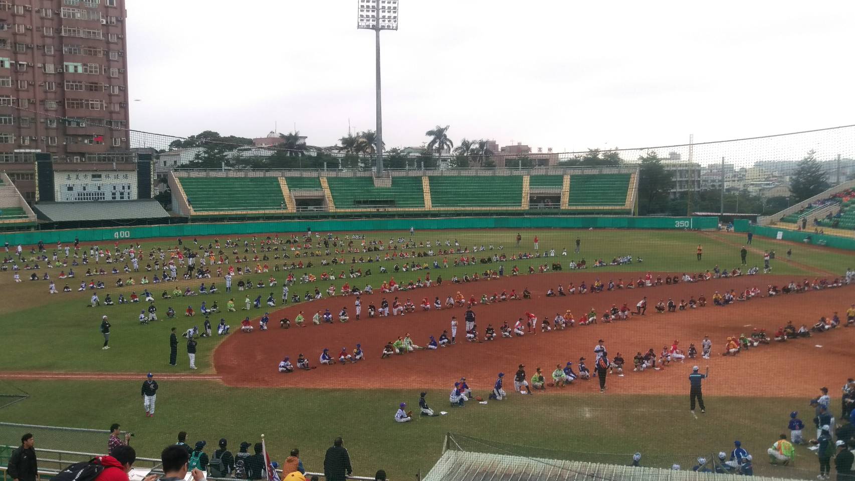 諸羅山盃軟式少棒賽16日在嘉義市立棒球場舉辦開幕式，原希望挑戰「最多人連續傳接棒球」的金氏世界紀錄，卻讓孩子們頂著寒風餓肚子傳接球，招來批評。（讀者提供）