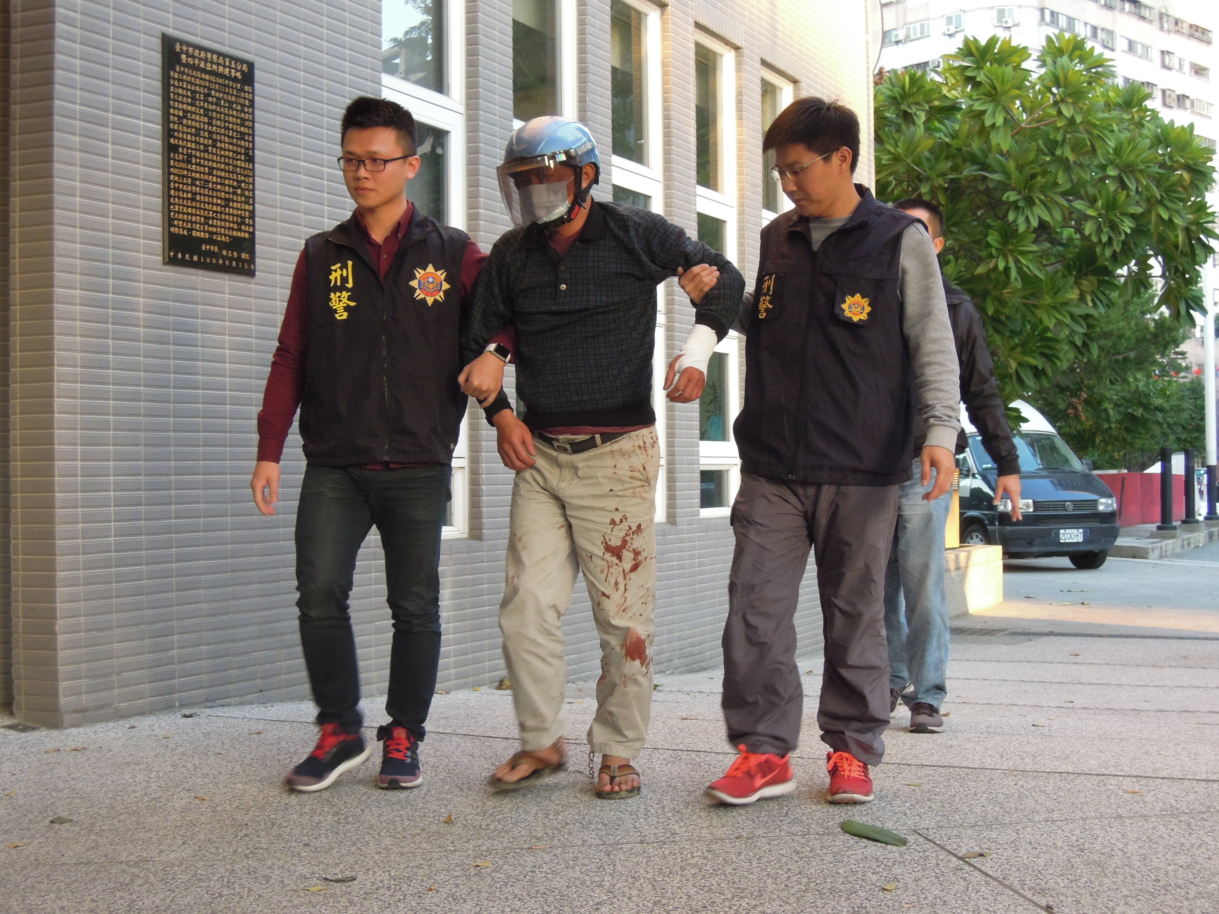 警方押解嫌犯范金彪，他身上還沾染死者的血跡。