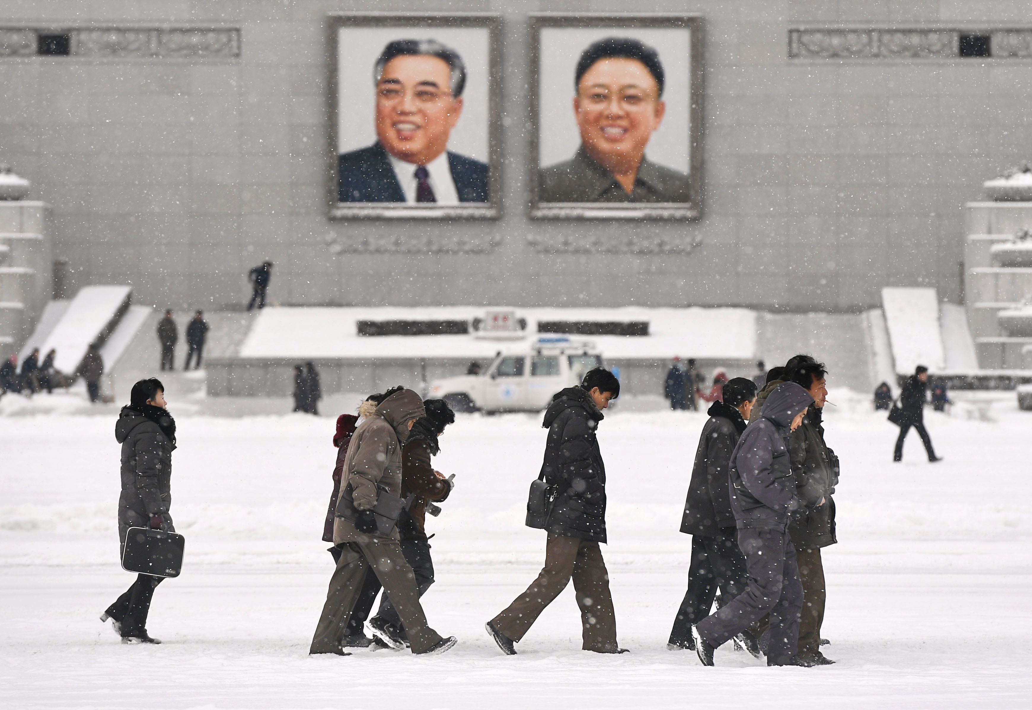 2017年12月20日，平壤，北韓民眾走過懸掛金日成父子巨大肖像的金日成廣場。（東方IC）