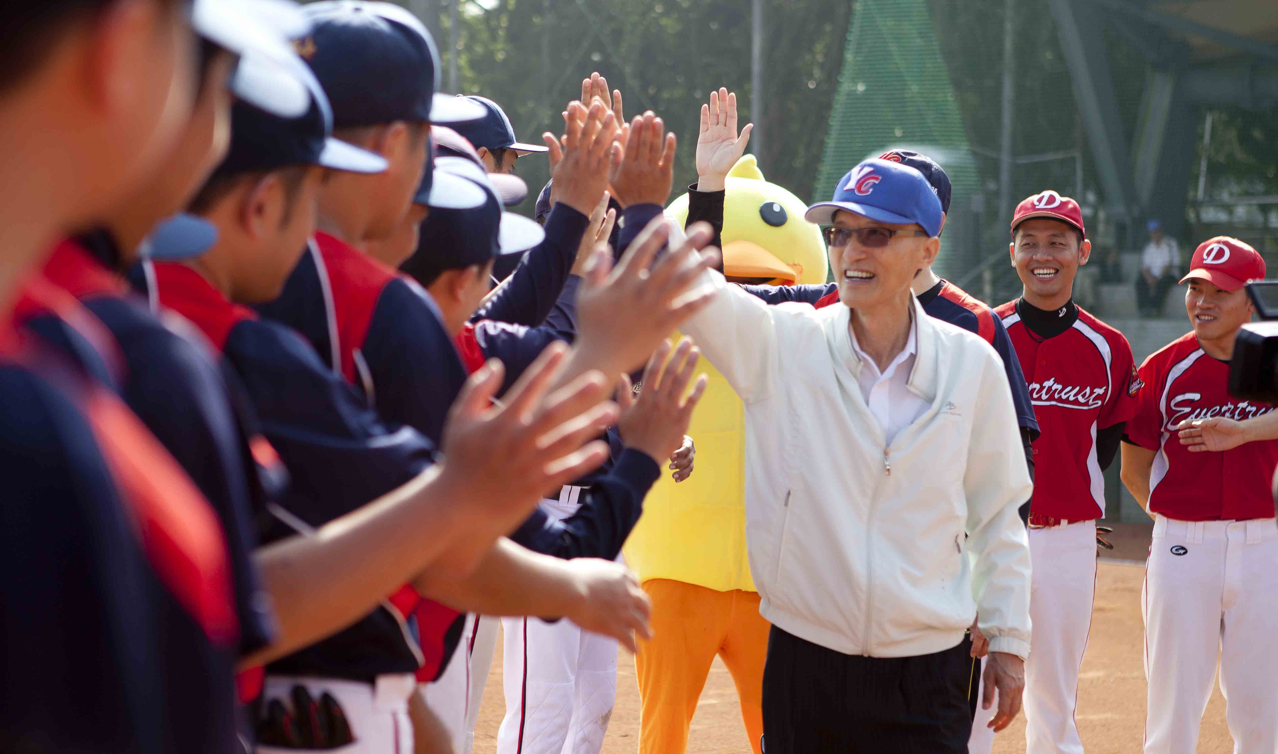 永慶房產集團董事長孫慶餘參加集團舉辦球賽,開心與員工擊掌。