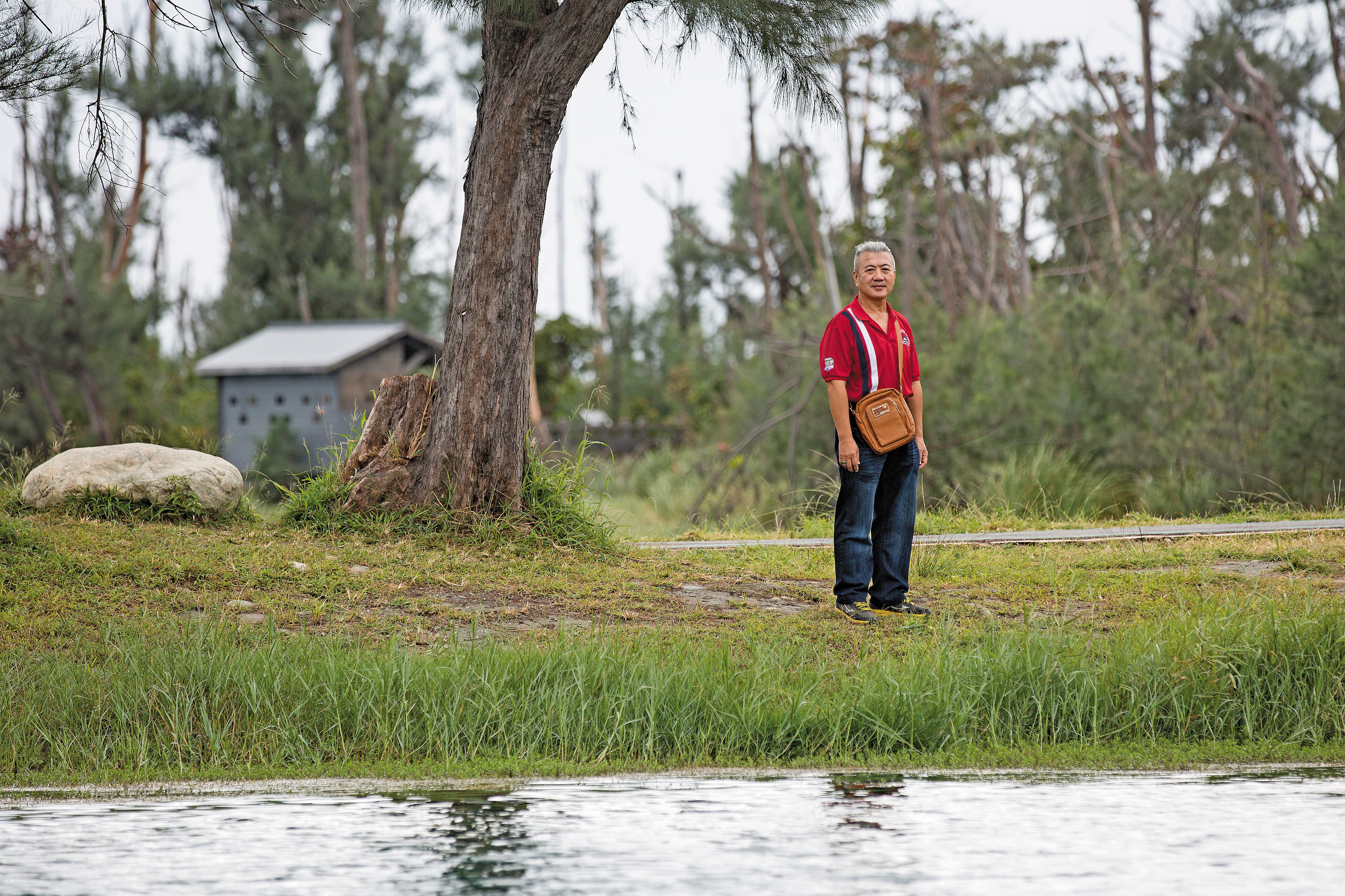 陳進山站在琵琶湖邊，神情平靜，背著妻子留下的包包，他說即使妻子在世，包包也一樣由他來背。