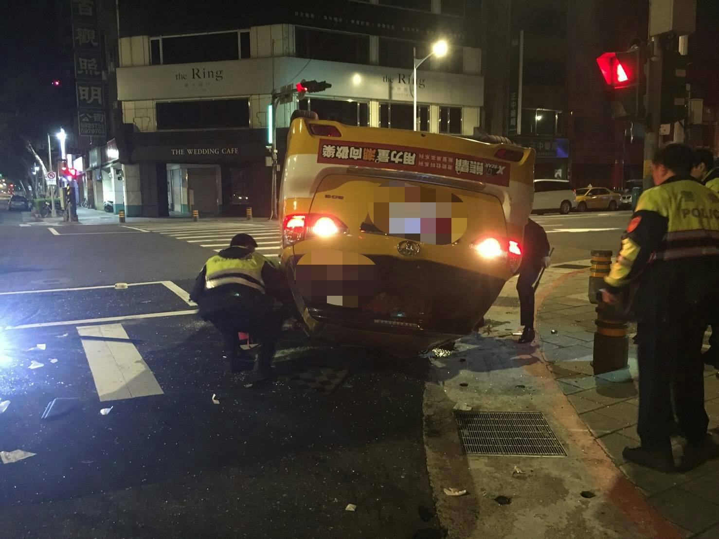 林男所駕駛的計程車因闖紅燈遭高速攔腰撞擊,撞上路邊護欄車底朝天。(警方提供)