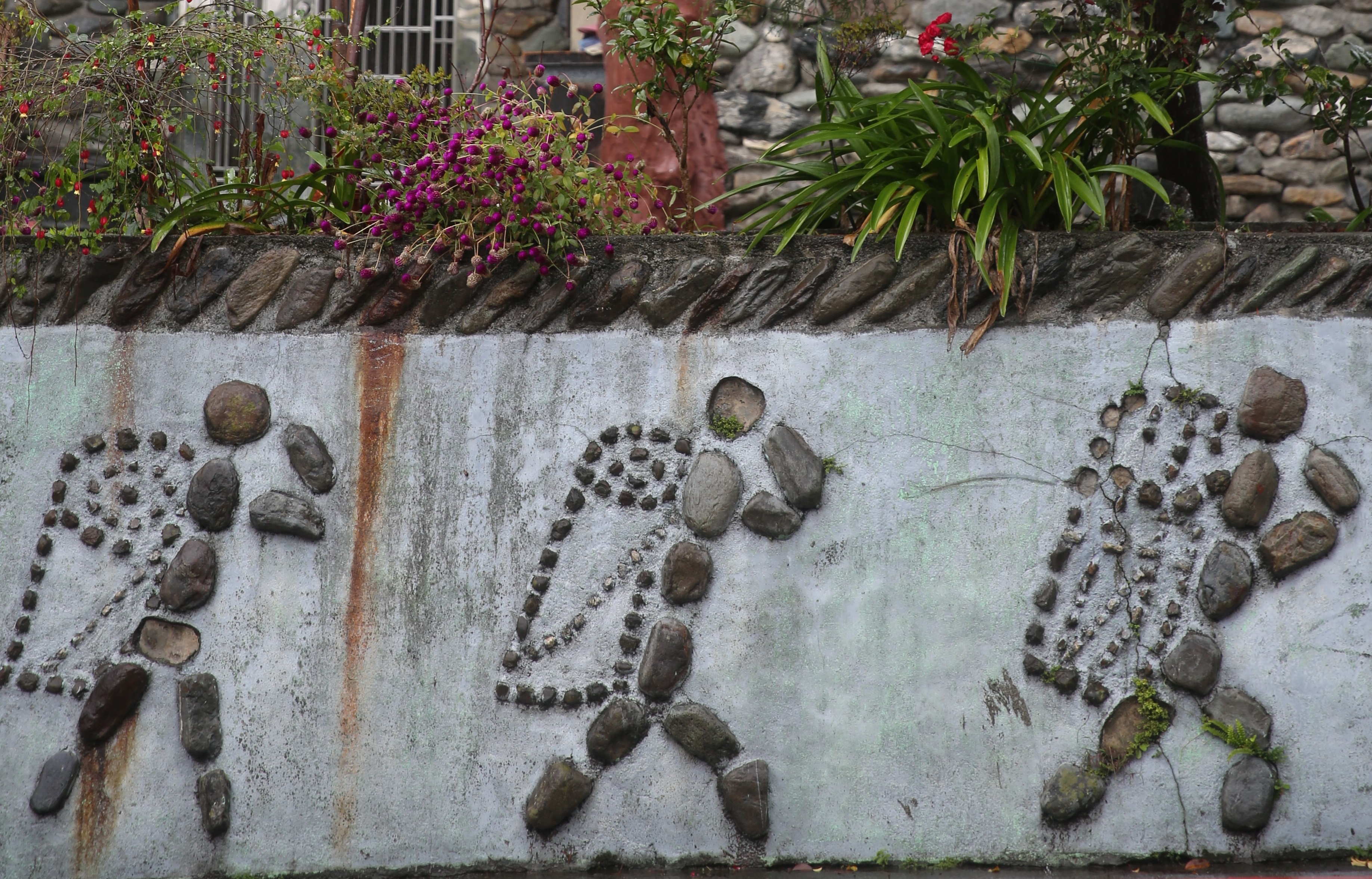 在望鄉部落，路旁圍牆上不時都能看見粗獷又饒富趣味的石頭畫。
