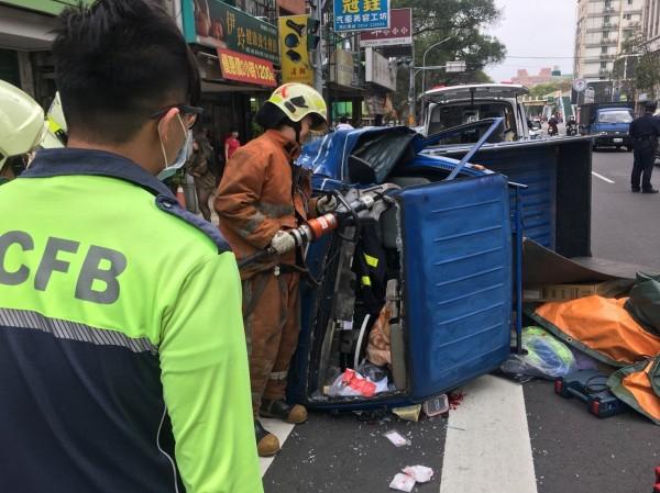 消防人員以油壓破壞器材及撬棒破壞車體，救出受困司機。(消防局提供)