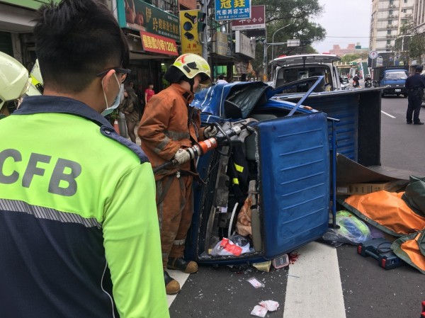 消防人員以油壓破壞器材及撬棒破壞車體，救出受困司機。(消防局提供)