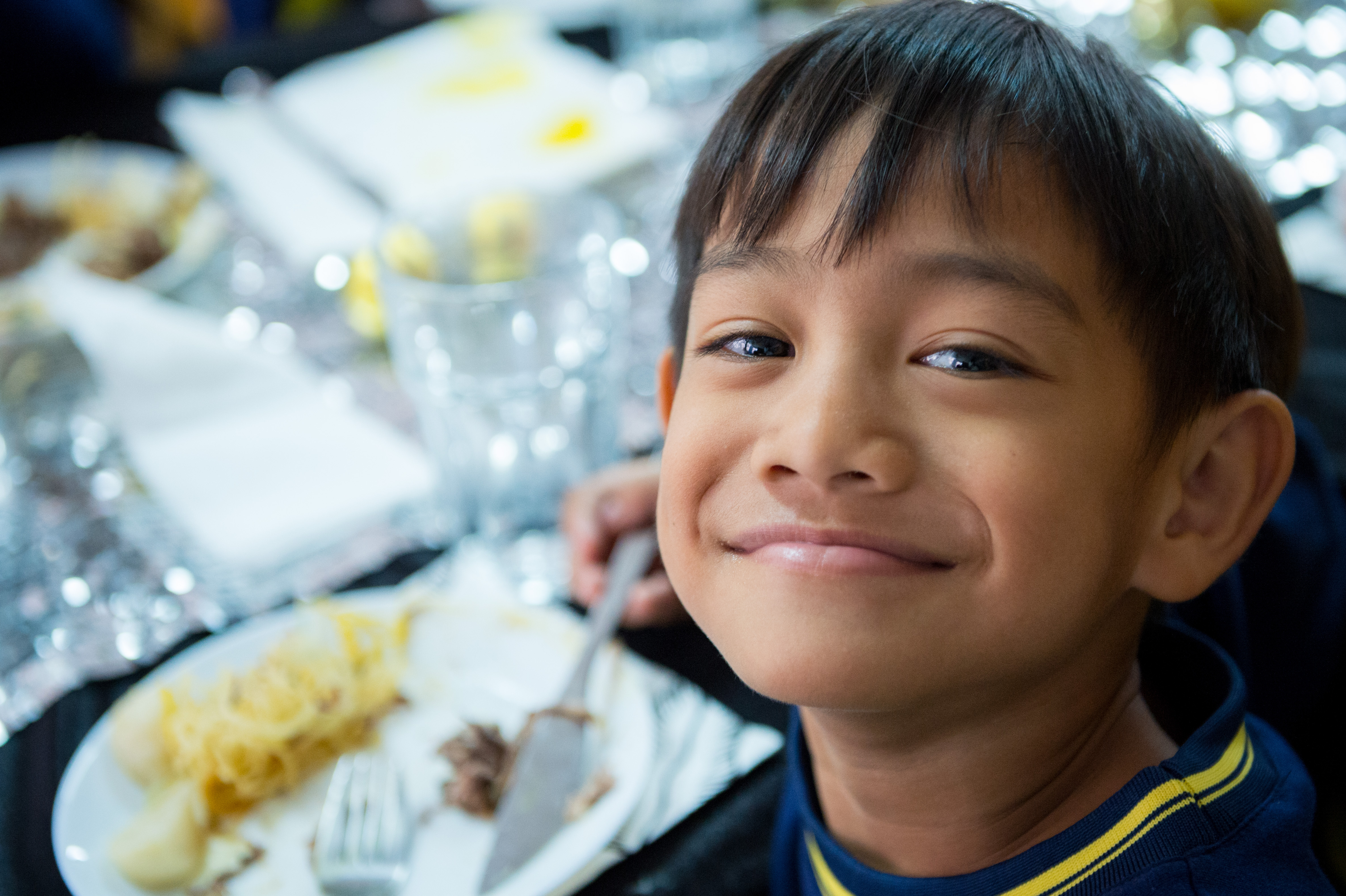 部落孩子坐在一日限定的法國餐廳，邊吃美食邊揚起笑臉。