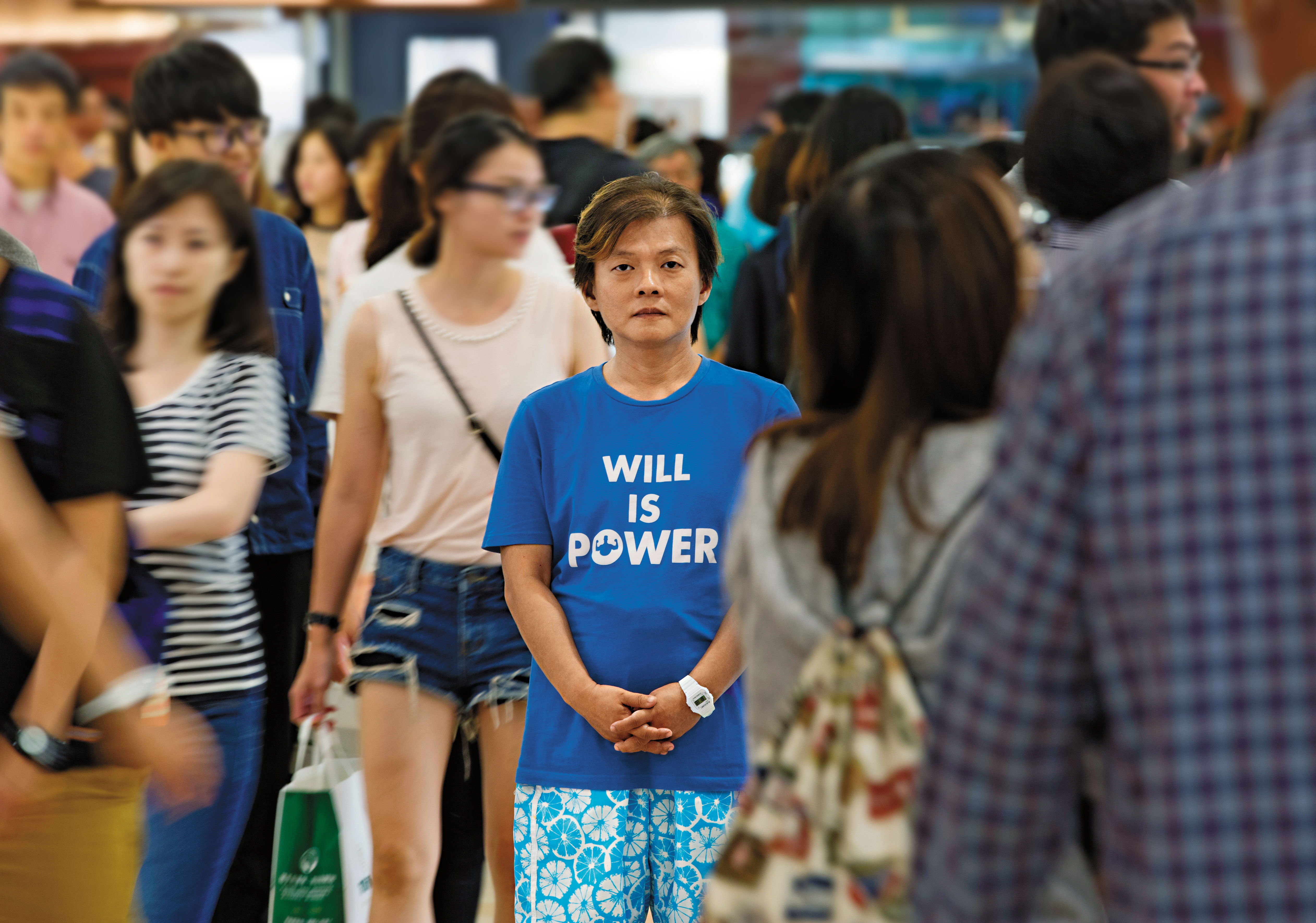 站在人群中，丘愛芝顯得更嬌小，他的生命故事深沉，但堅強的意志給了他面對自我的力量，如同T恤上的標語。