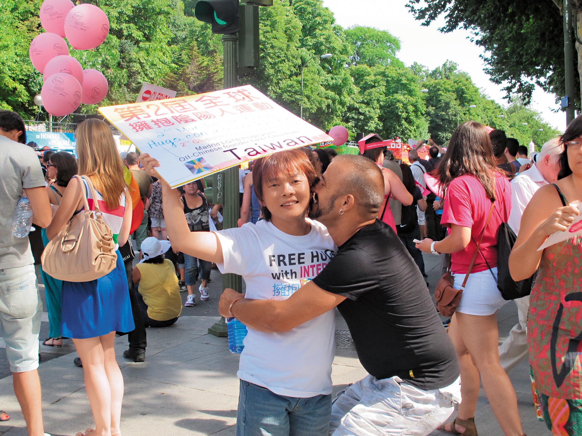 10年來,丘愛芝參加國際陰陽人運動與同志運動,造訪數十個國家,見過上百位陰陽人,他總是隨身攜帶著「擁抱陰陽人」的標語牌子。(丘愛芝提供)