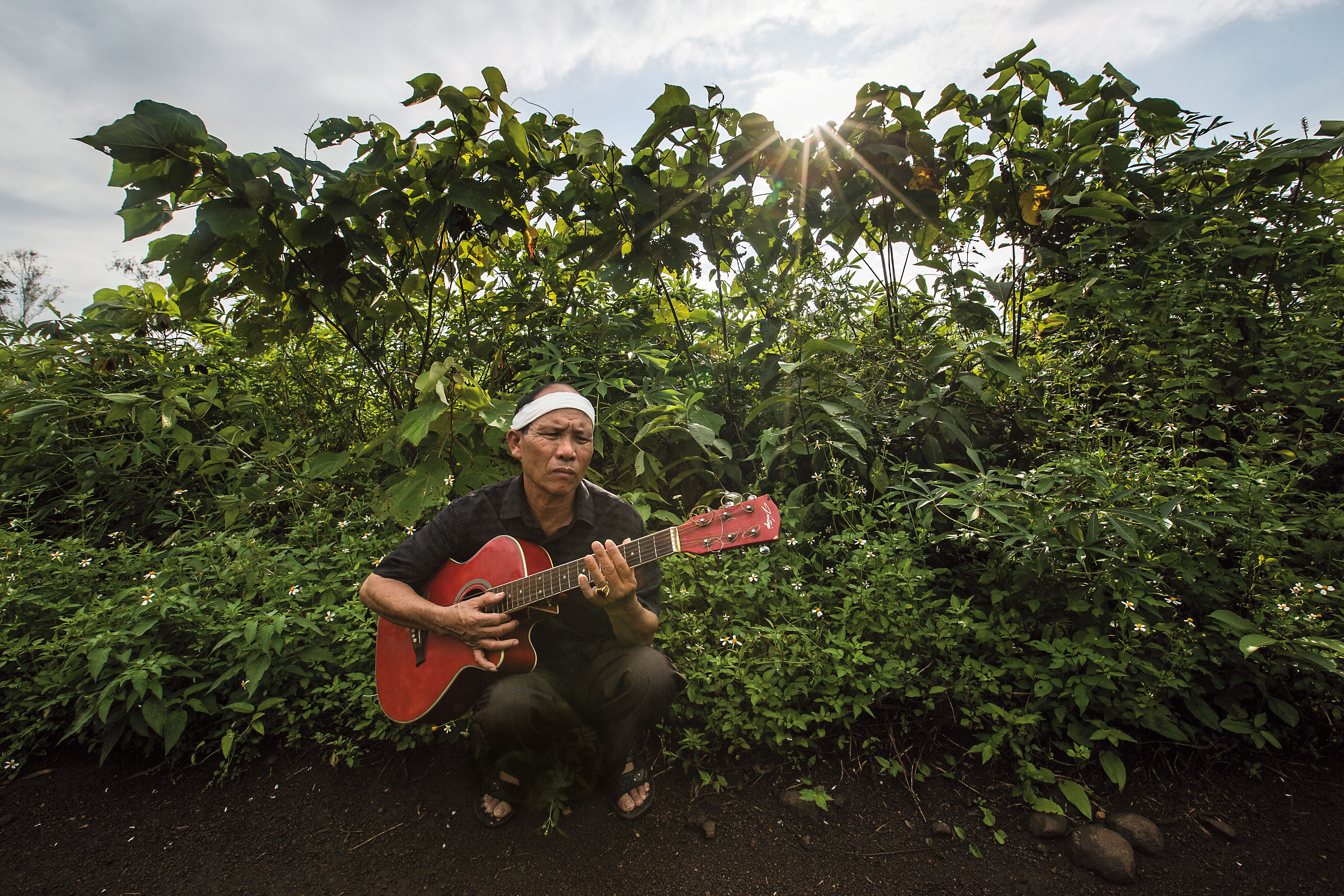 抱著阮國非生前最愛的吉他，站在準備給他養牛的土地前，父親阮國同（圖）心中有無限悲傷。