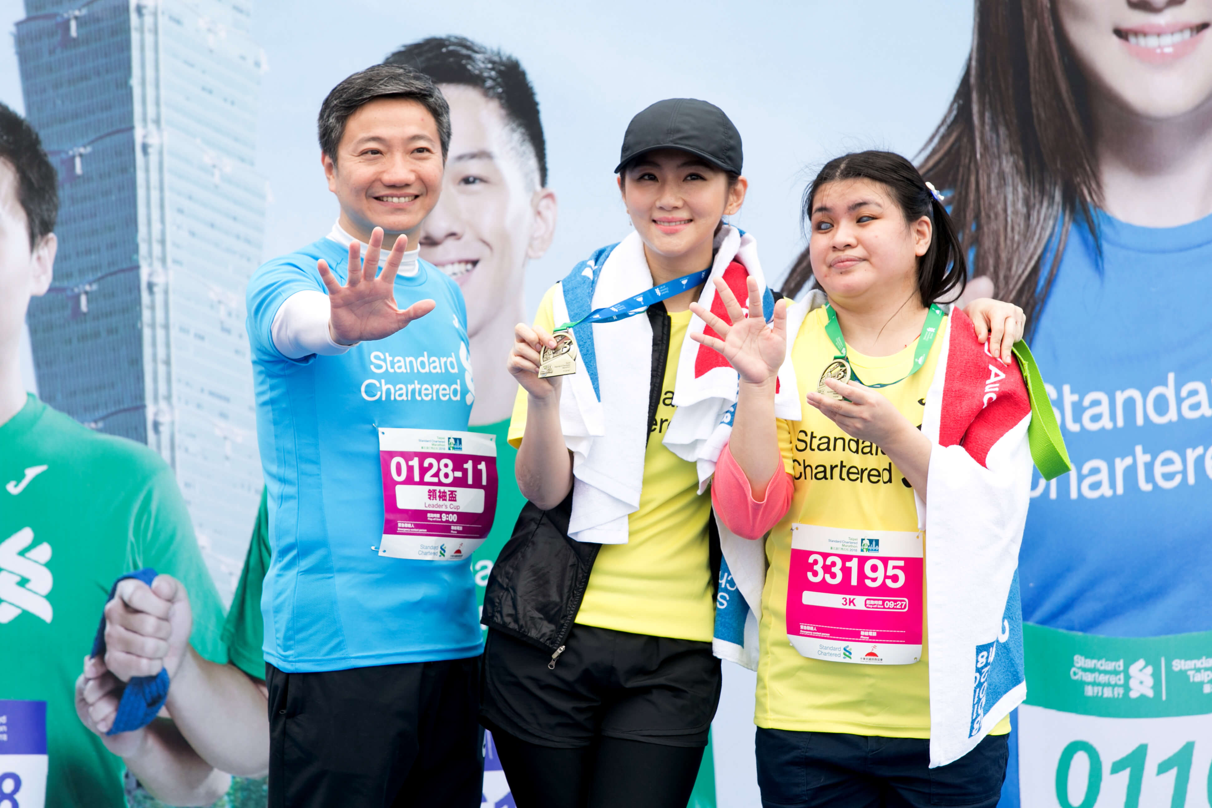 渣打銀行總經理林遠棟（左），為成功完賽的Selina（中）與視障跑友穎芝掛上完賽獎牌。（渣打銀行提供）