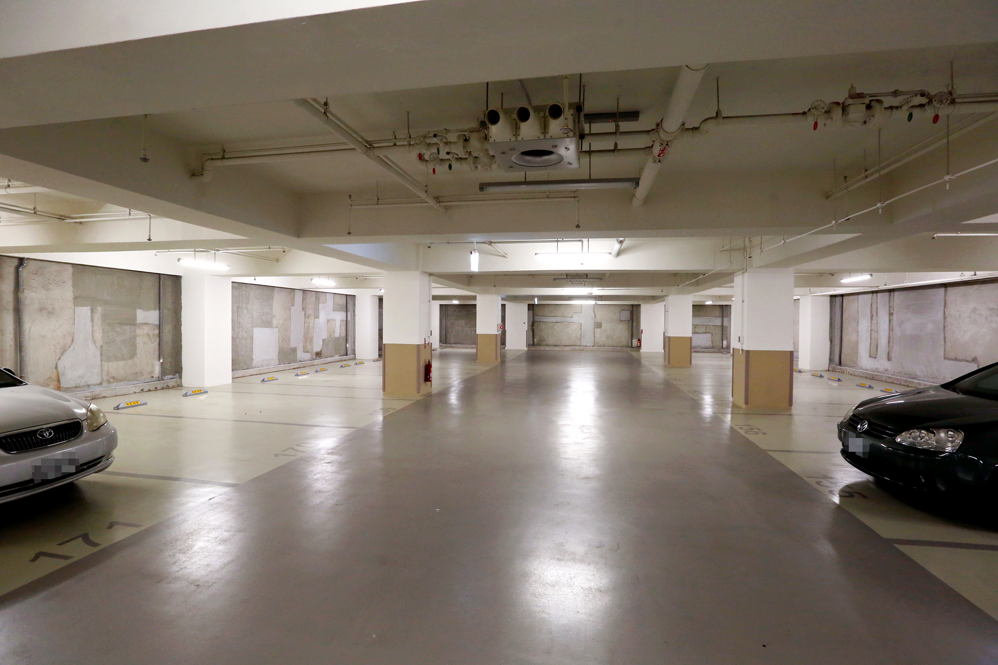 住戶陳小姐帶本刊走訪頤湖苑地下室，指出拆掉複壁後的牆面，近黃色處為舊牆，其餘皆為修補處。