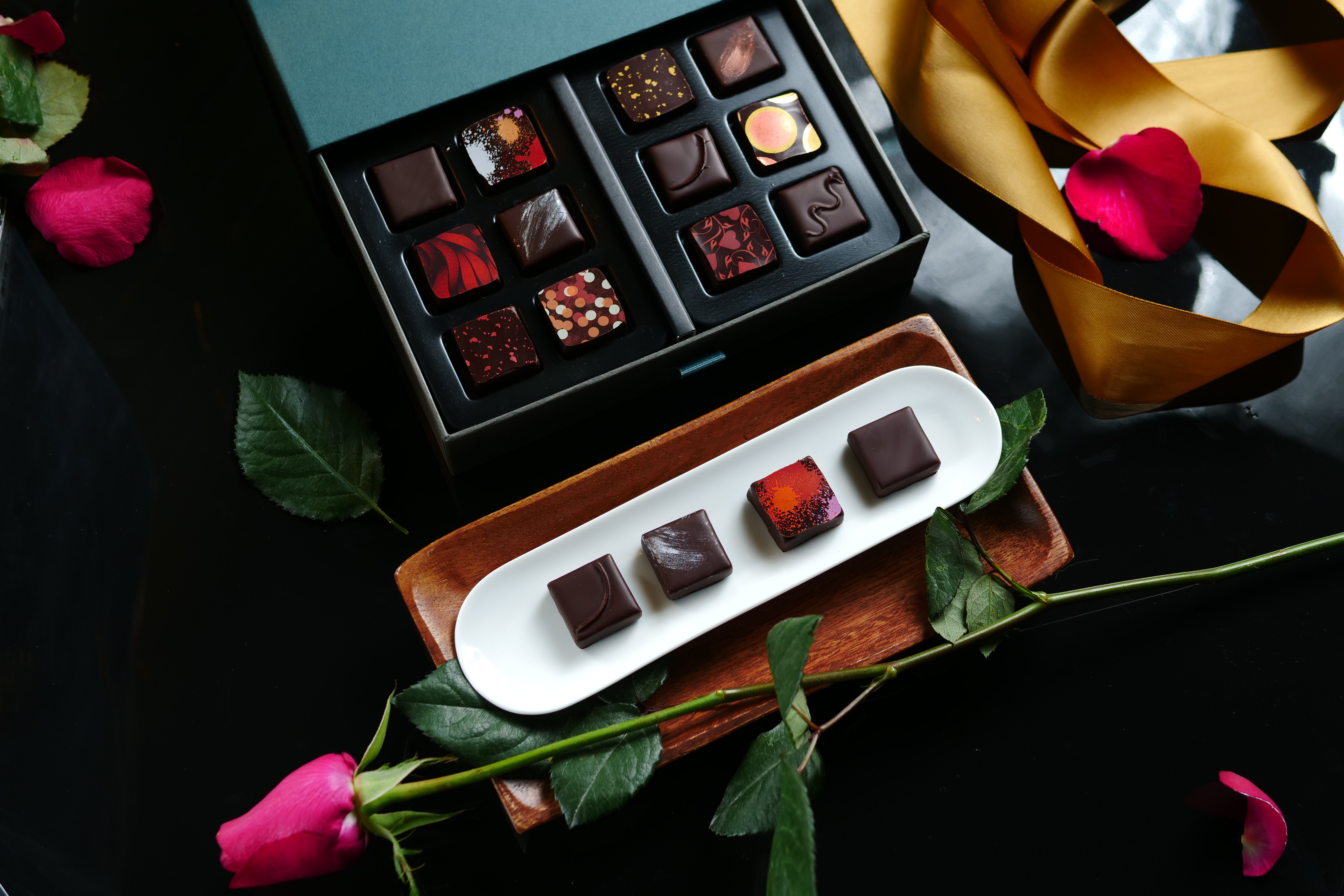 夾心巧克力「台灣」「一翦梅」「百香薑花」「陳釀醬油」，放入嘴裡要用咬的，同時感受甘苦、滑順及各種香氣。（白盤內由右向左，85元／單片、1,200元／12入） 