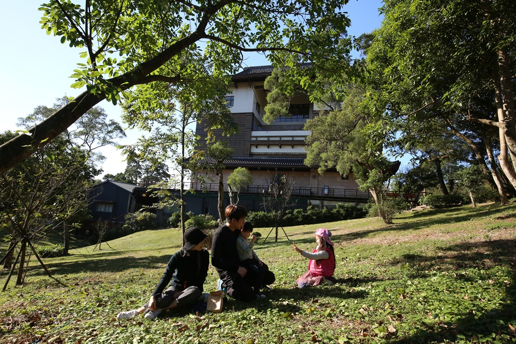 親子朋友坐在園區草地，享受清閒時刻。