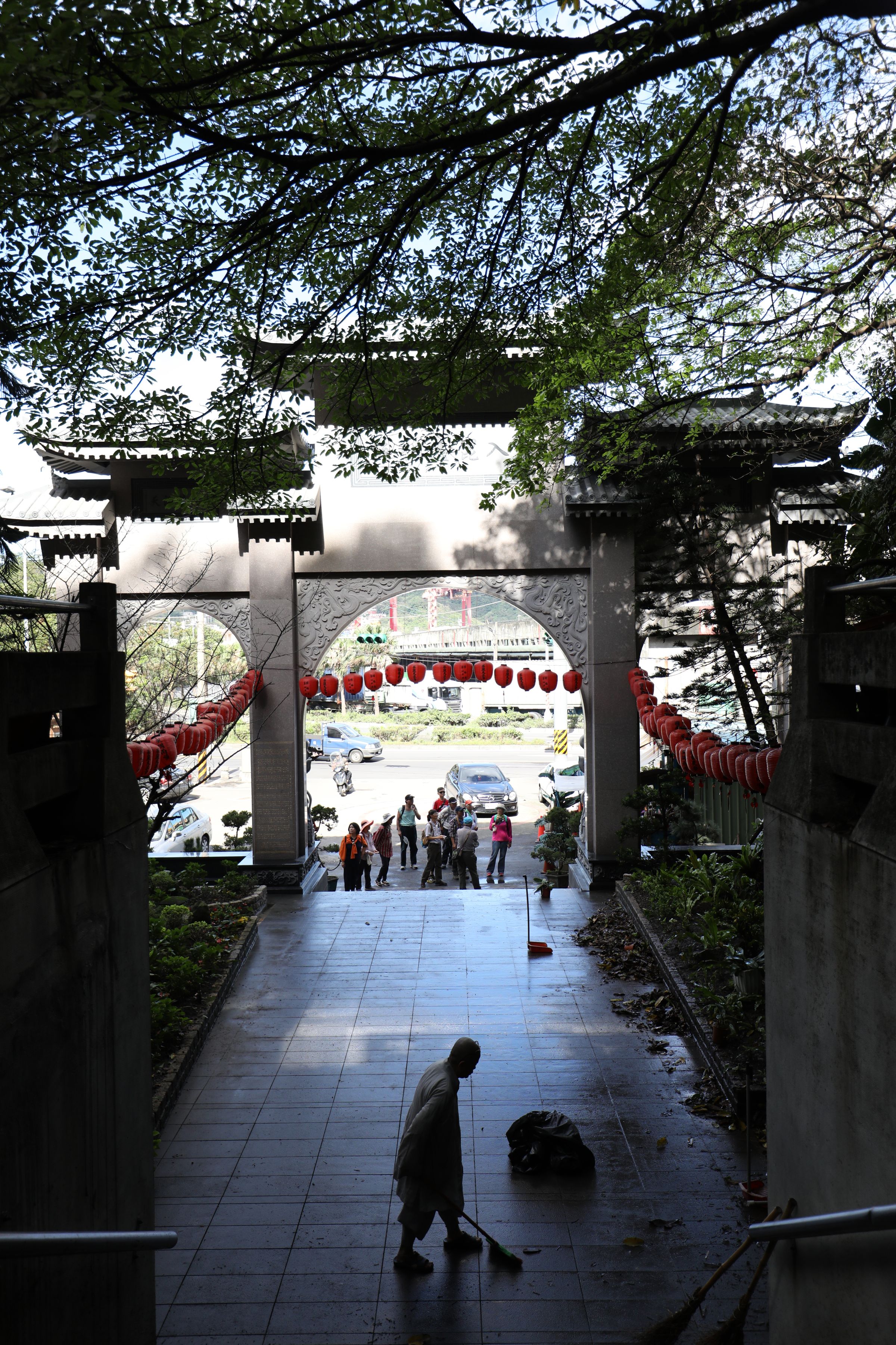 出家人在廟堂外清掃，山門正對著碼頭。