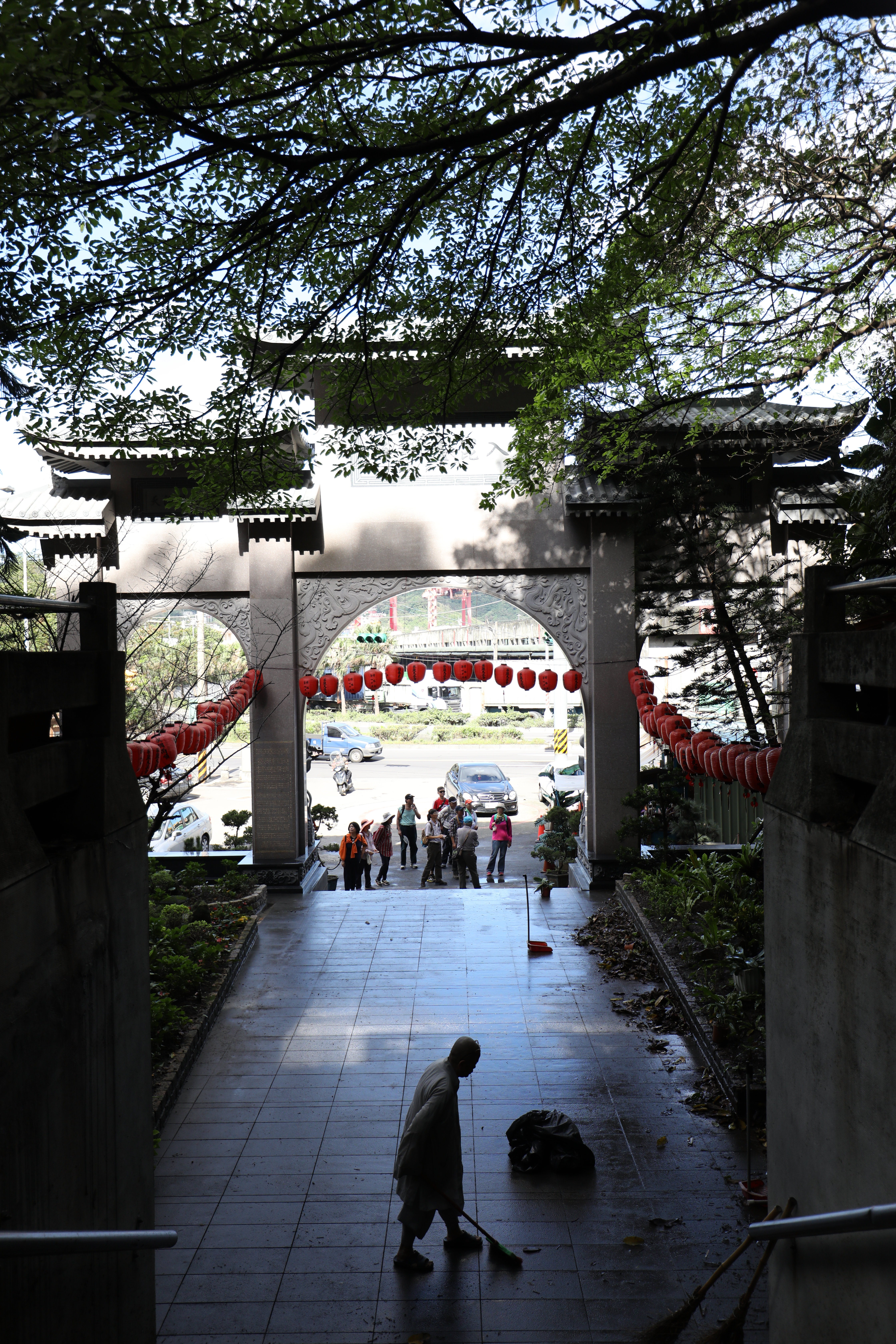 出家人在廟堂外清掃，山門正對著碼頭。