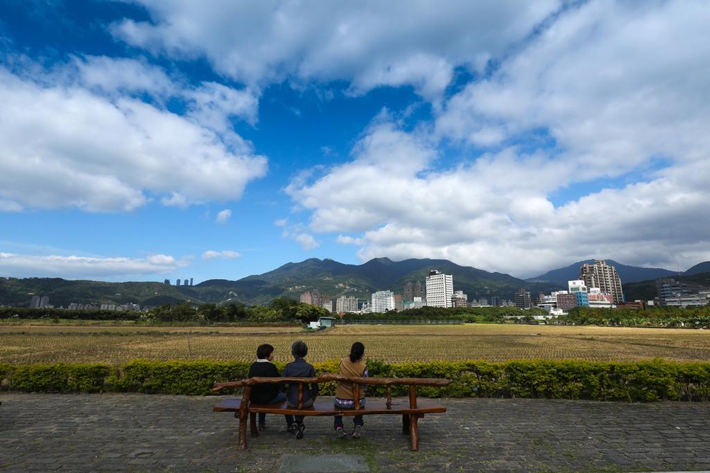 旅人坐在木椅,靜心享受眼前的山景稻田。