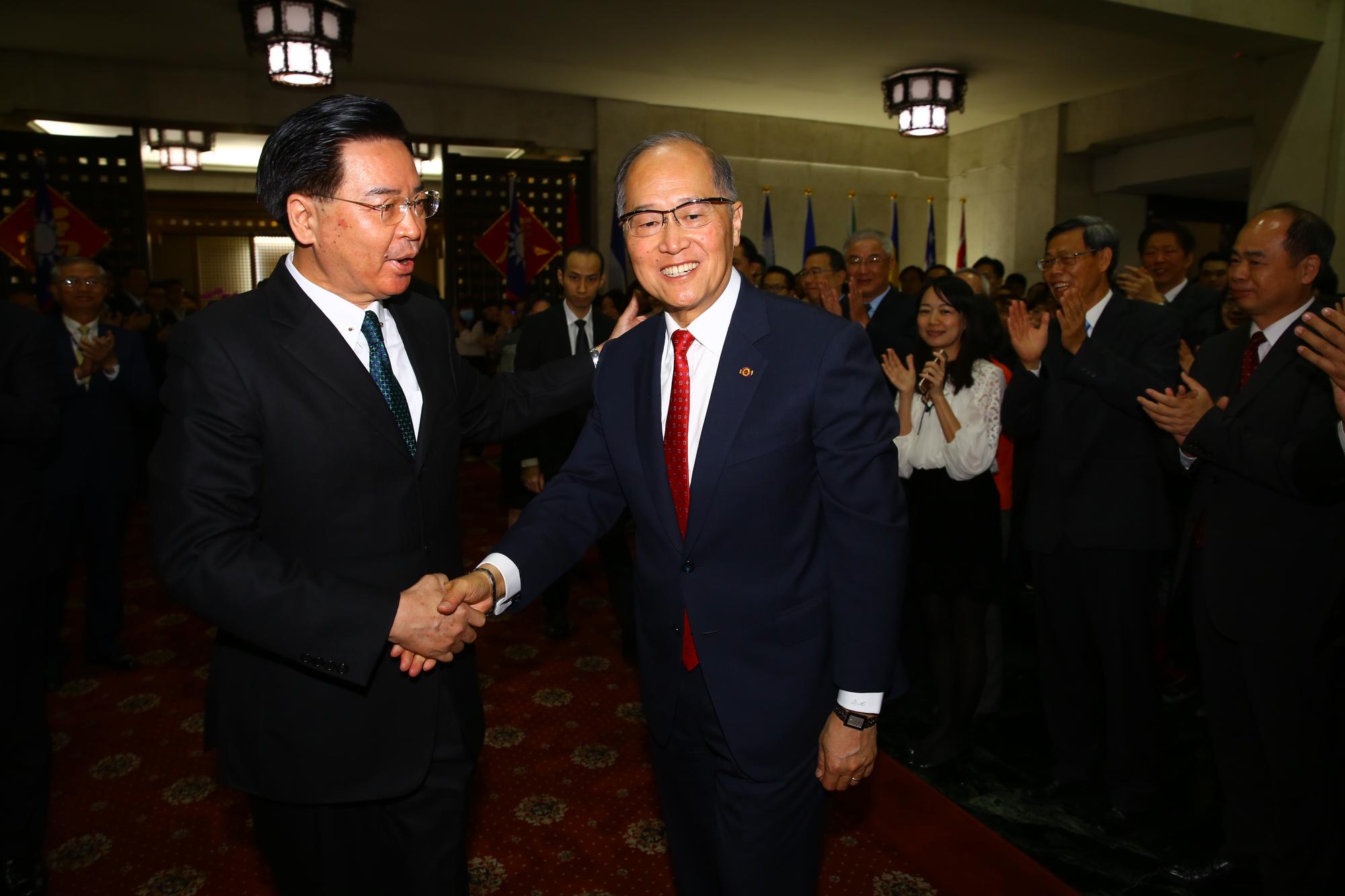 新任部長吳釗燮(左)與卸任部長李大維(右)在外交部同仁前握手致意。